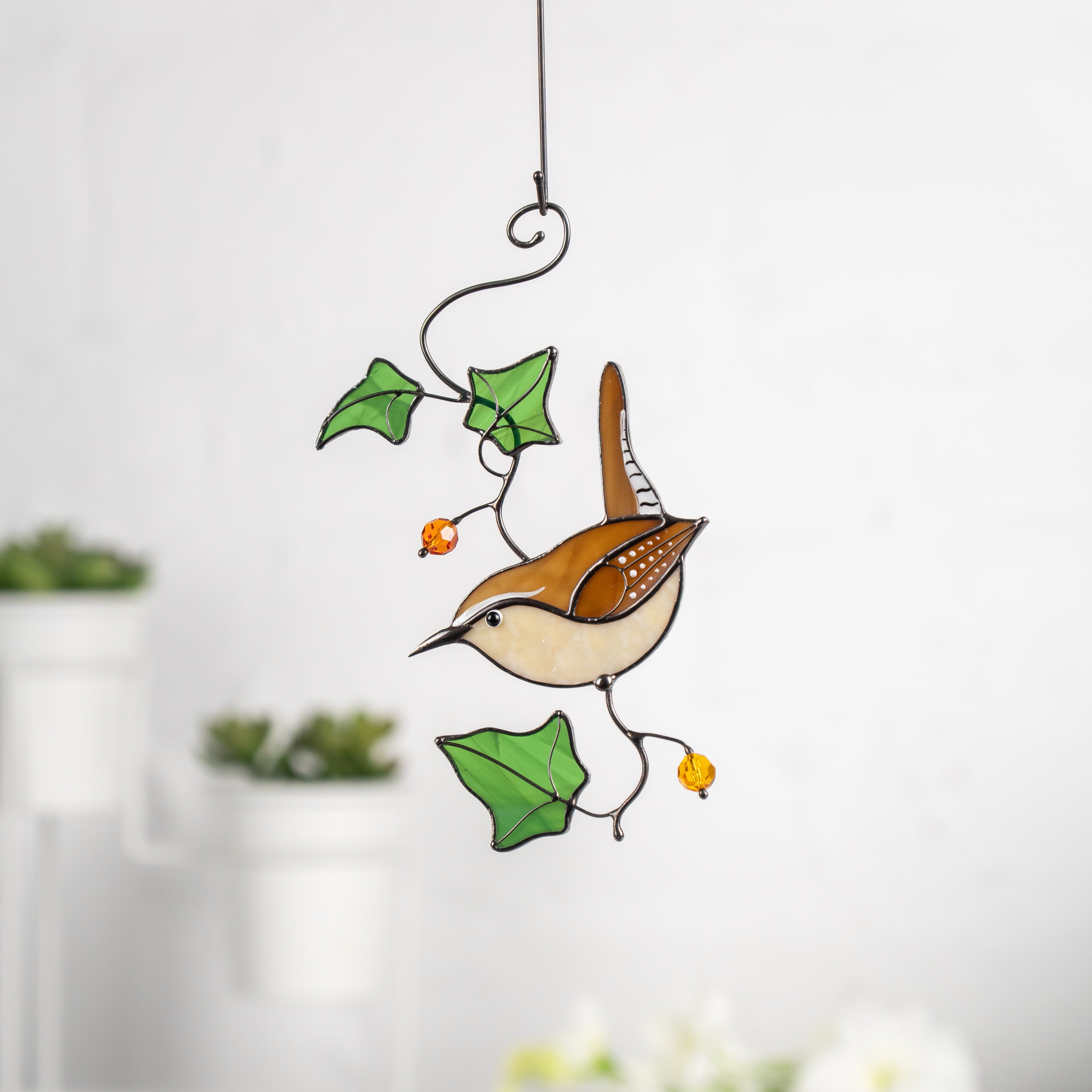 Carolina wren stained glass suncatcher hanging on a white background with green ivy leaf details.