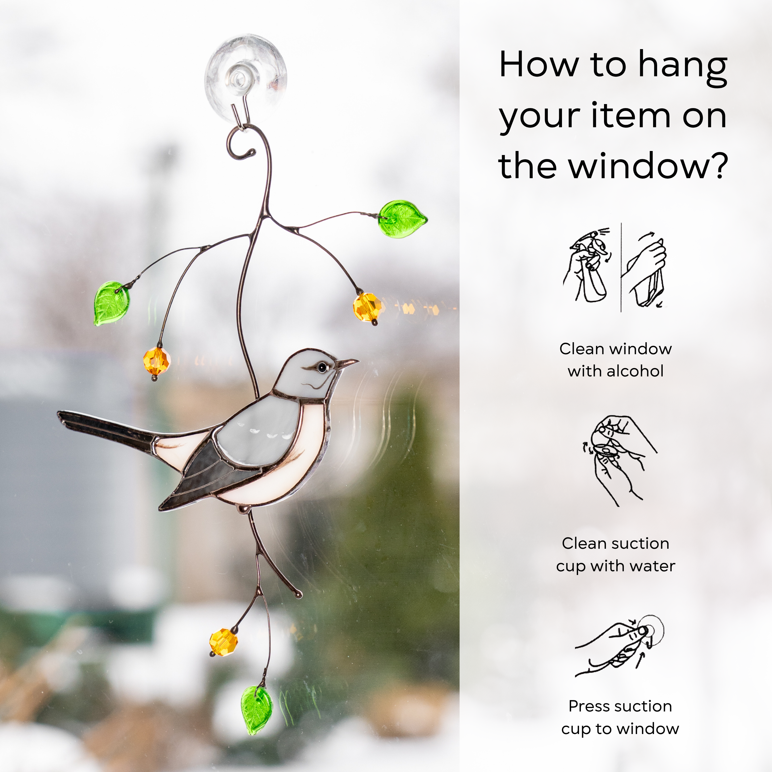 Stained glass mockingbird on a window using suction cup with snowy background, instruction for hanging: clean window and suction cup, press a cup to the surface.