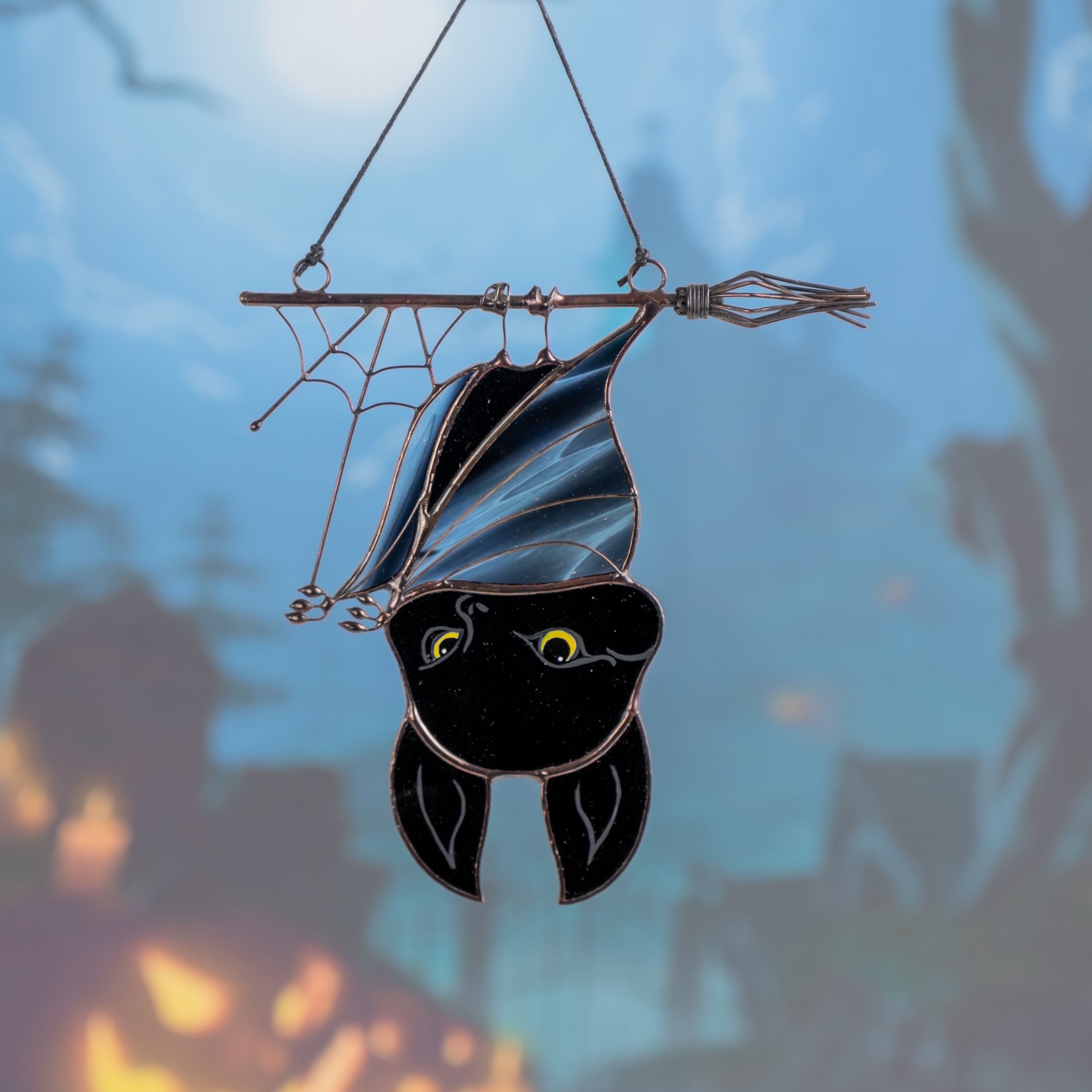 Stained glass Halloween bat hanging on broomstick with a spooky background, perfect seasonal decoration.