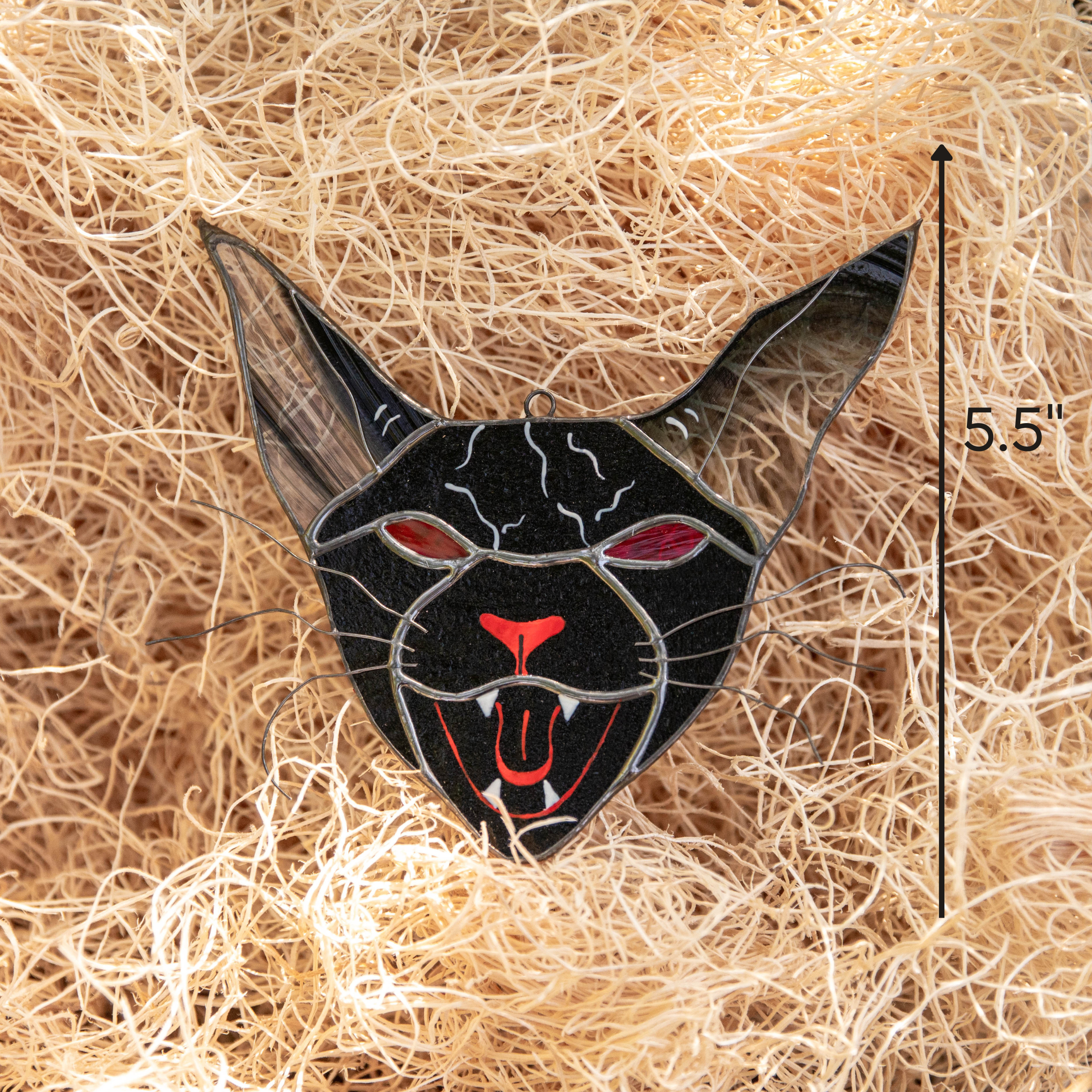 Stained glass Halloween cat with long black ears, red mouth, and sharp fangs shown in hay with 5.5-inch height note.
