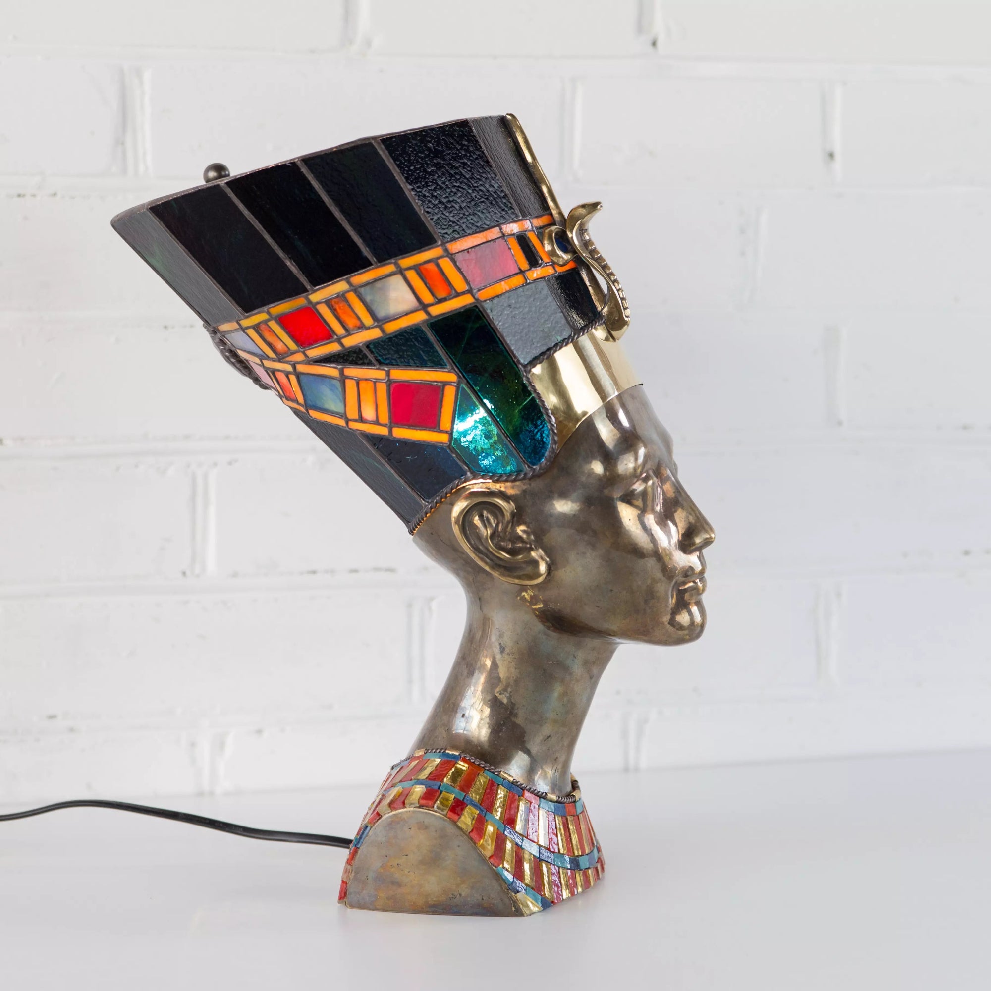 Close-up of stained glass panel showing Queen Nefertiti in profile with rich amber and blue glass