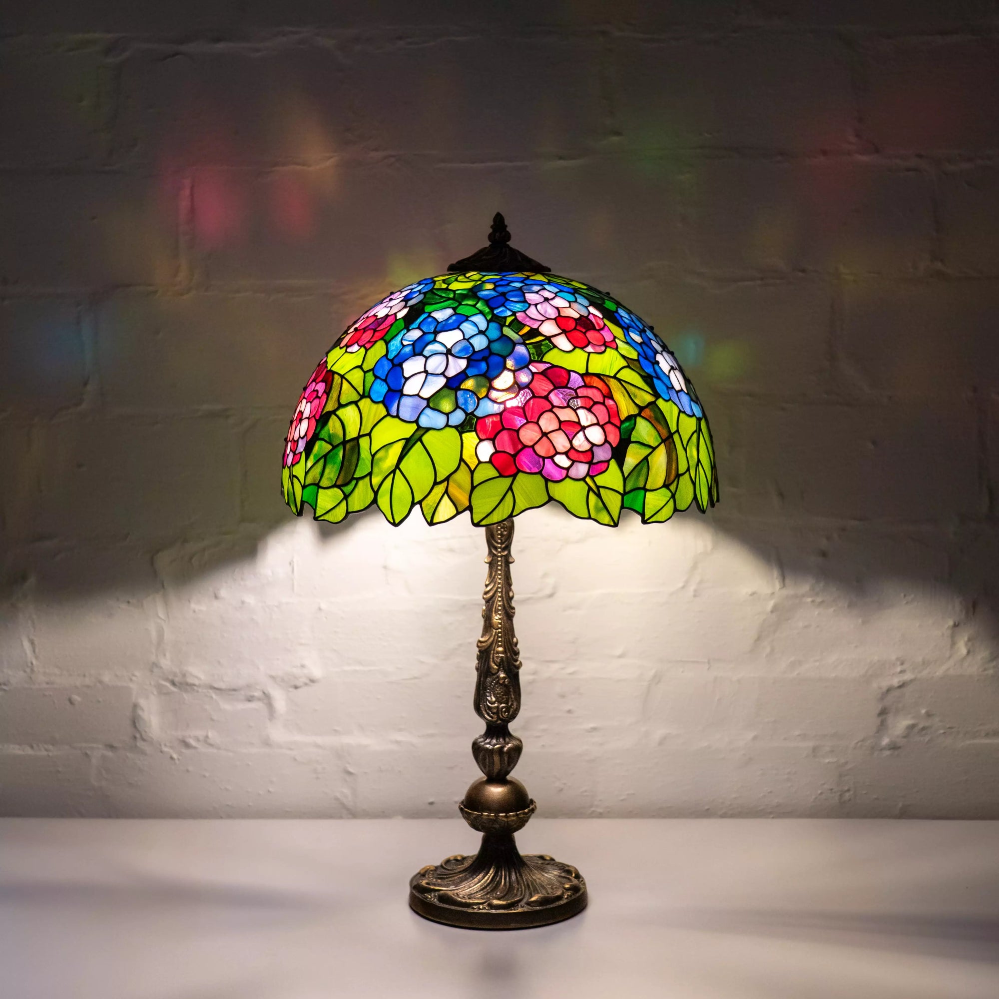 Stained glass lamp lights up a dark room with vivid flower patterns on the wall.