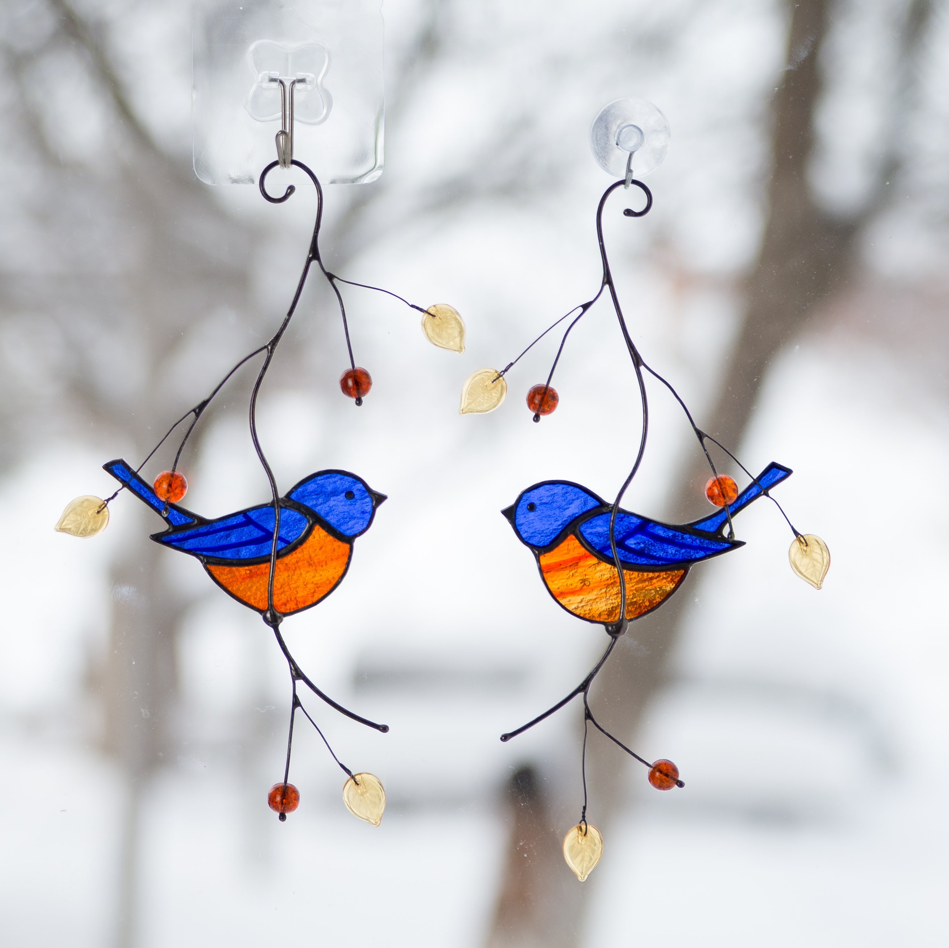 Stained glass birds on branches with a blurred natural background