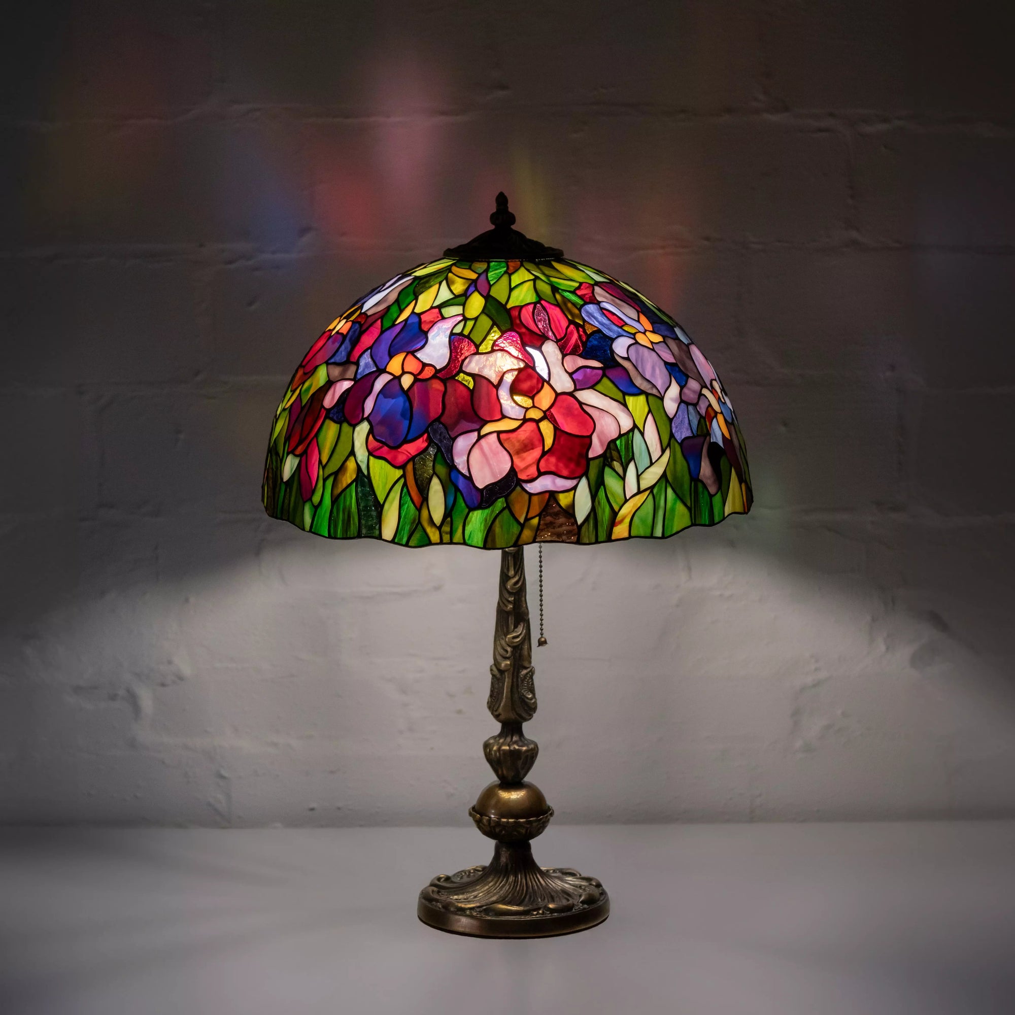 Full view of glowing iris floral glass lamp with warm colored reflections