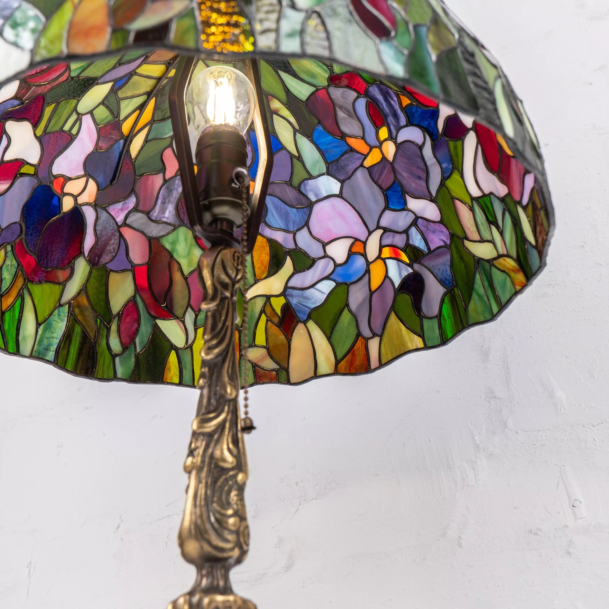 Inner view of the lamp with bulb visible through intricate floral glass shade
