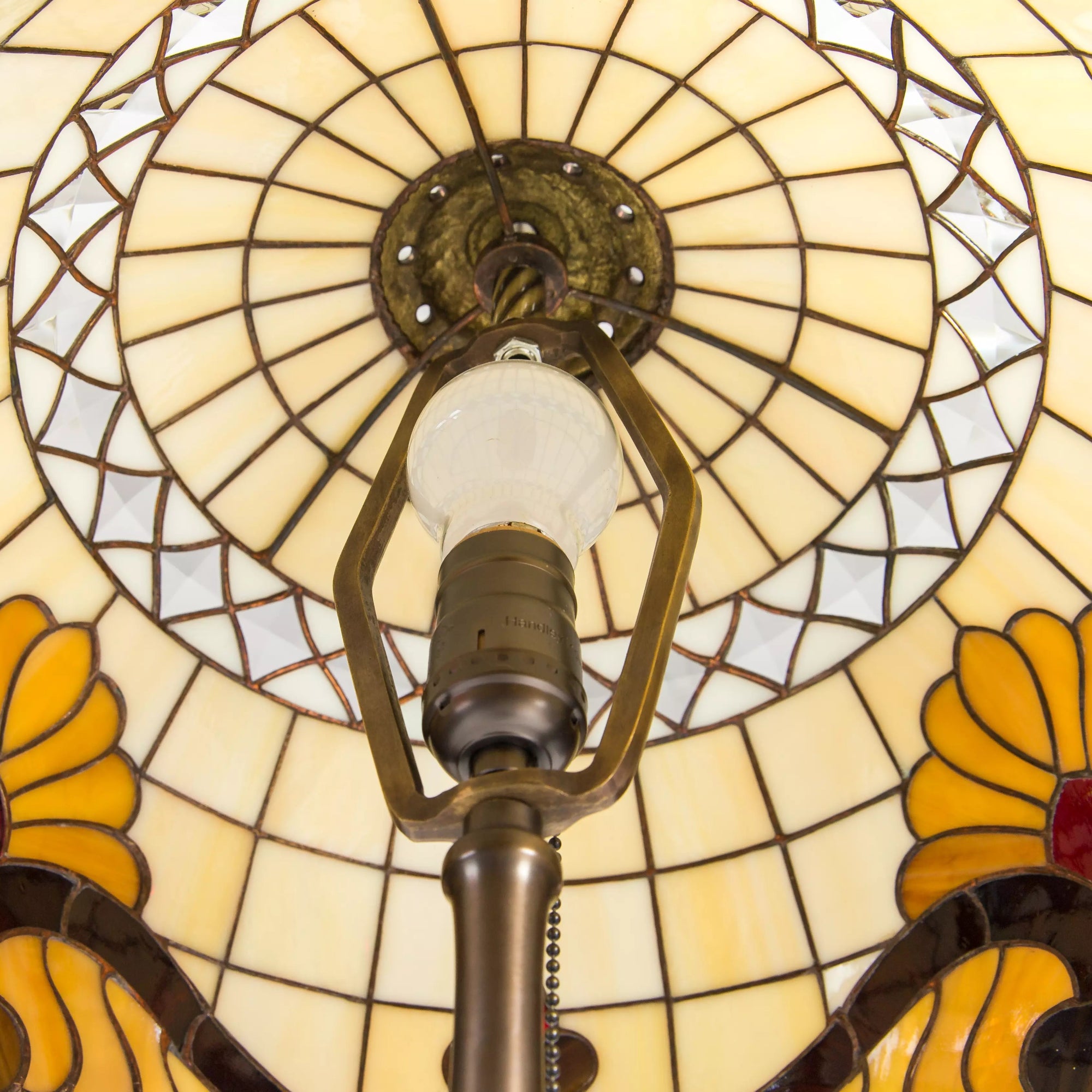 View from below stained glass lampshade with yellow floral pattern and bulb socket