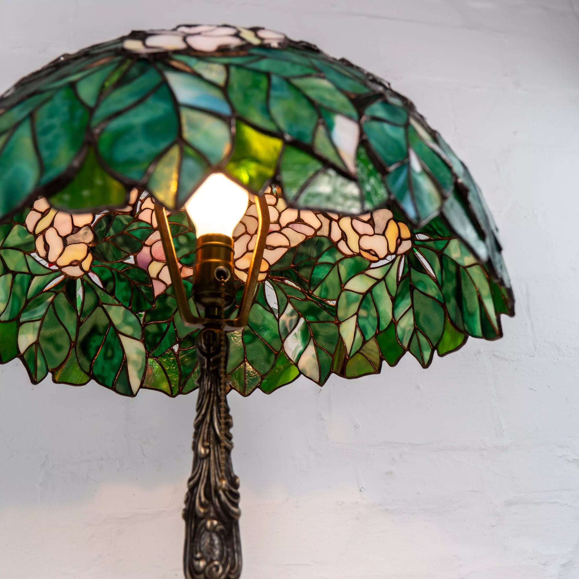 Interior of stained glass chestnut lamp with bulb and green leafy design