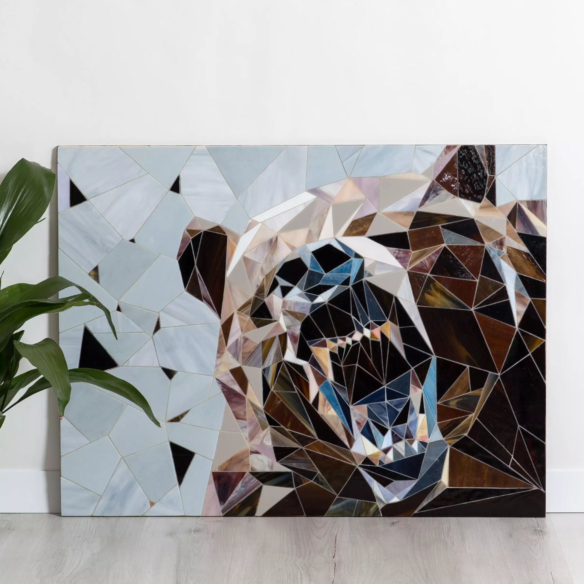 Bear mosaic with sharp angles and earthy glass shades shown in minimalist room with potted plant