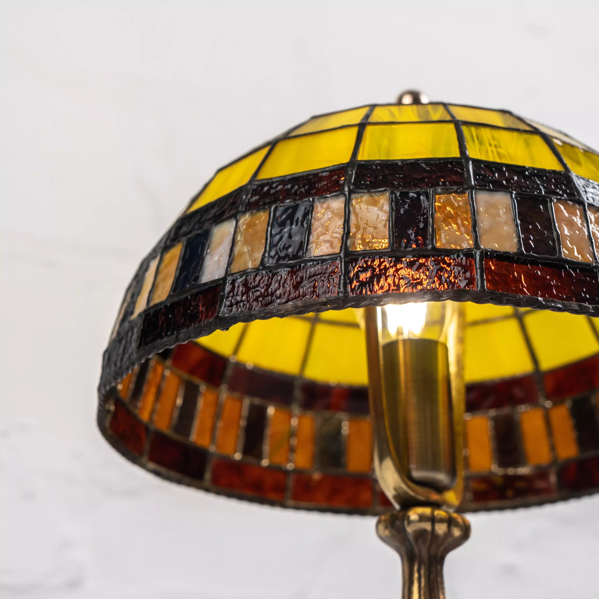 Under the dome of stained glass lamp showing rich amber, orange and yellow tones with bulb inside