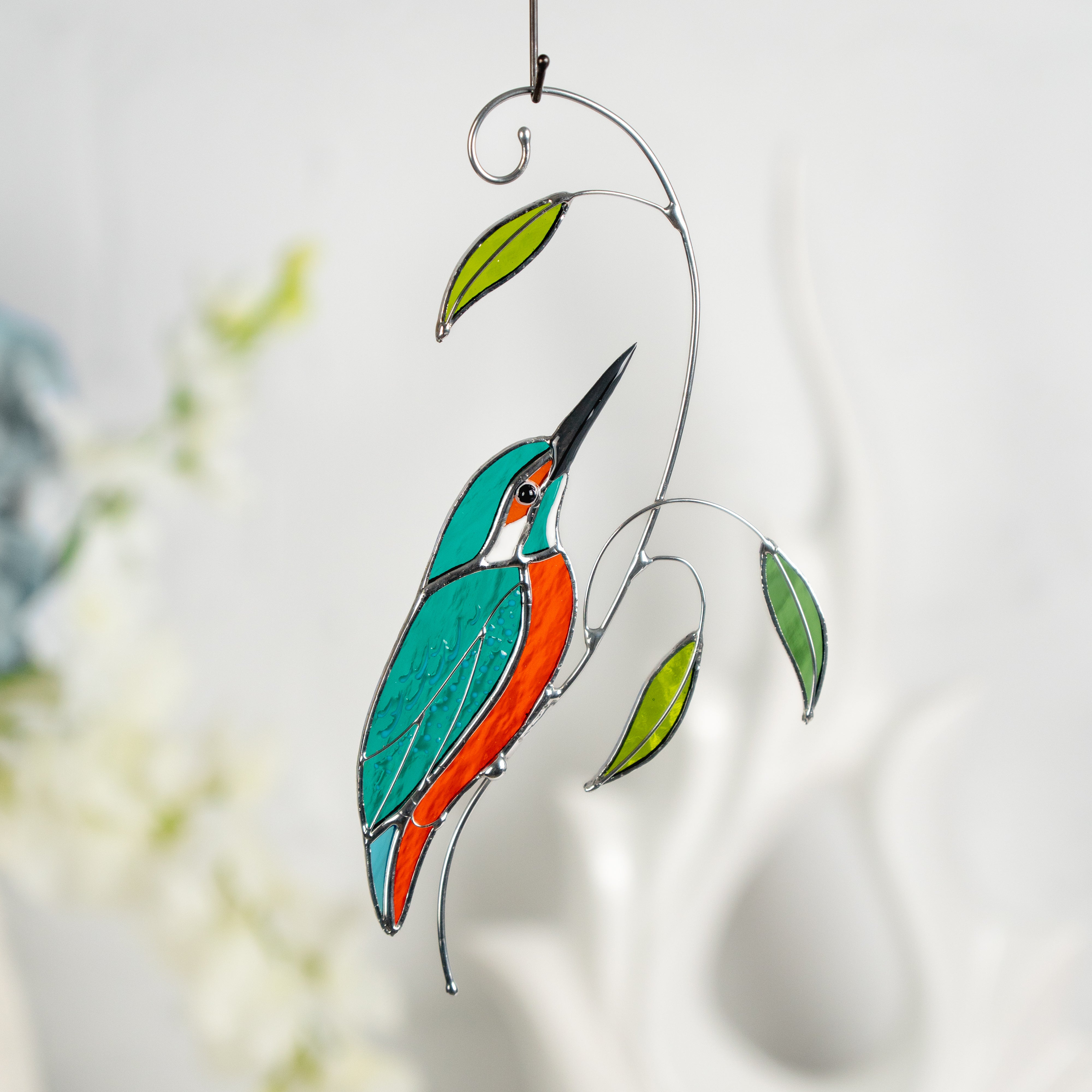 Stained glass kingfisher bird with graceful curves and bright green glass leaves.