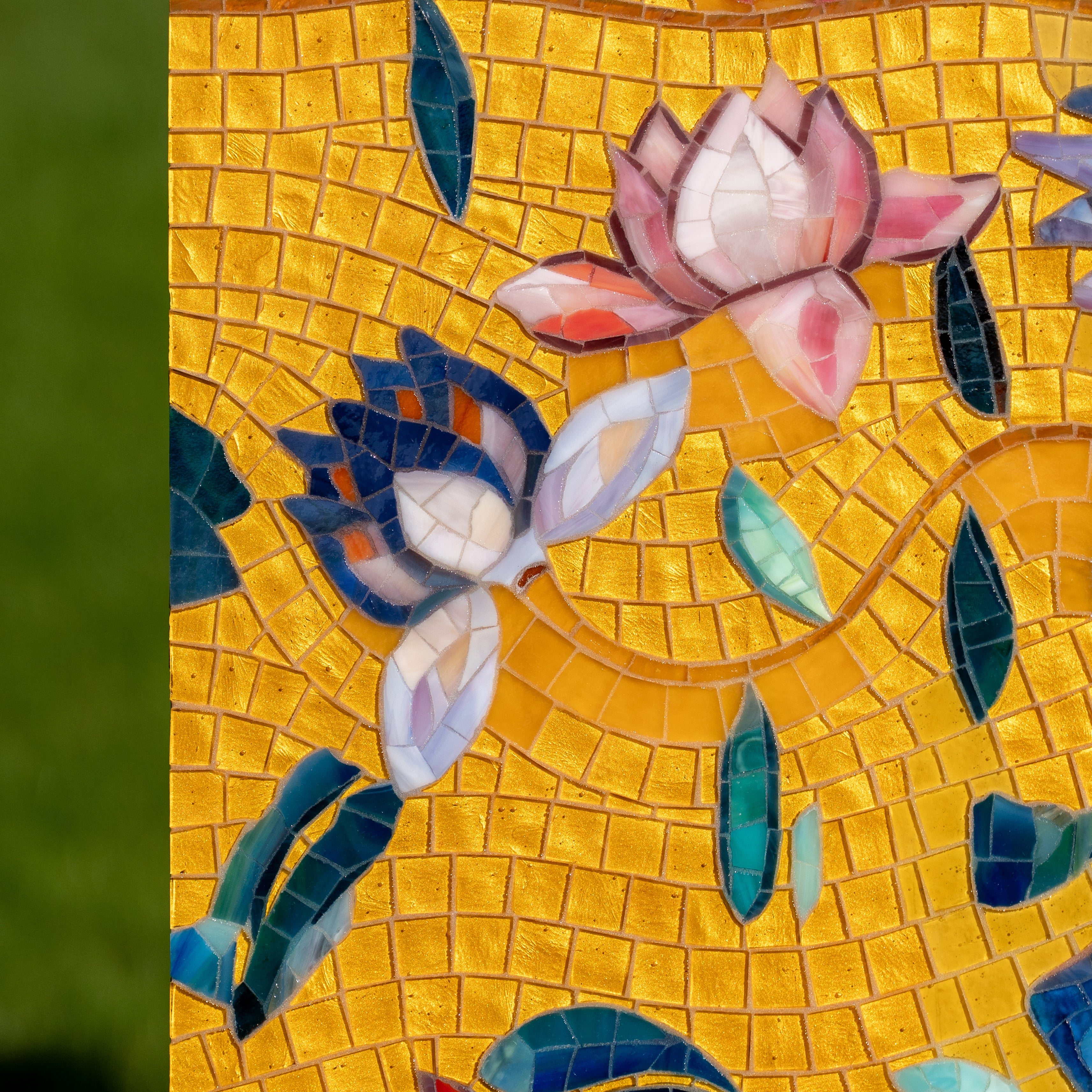 Close-up of stylized lotus flowers made from glass mosaic tiles, set against yellow mosaic.