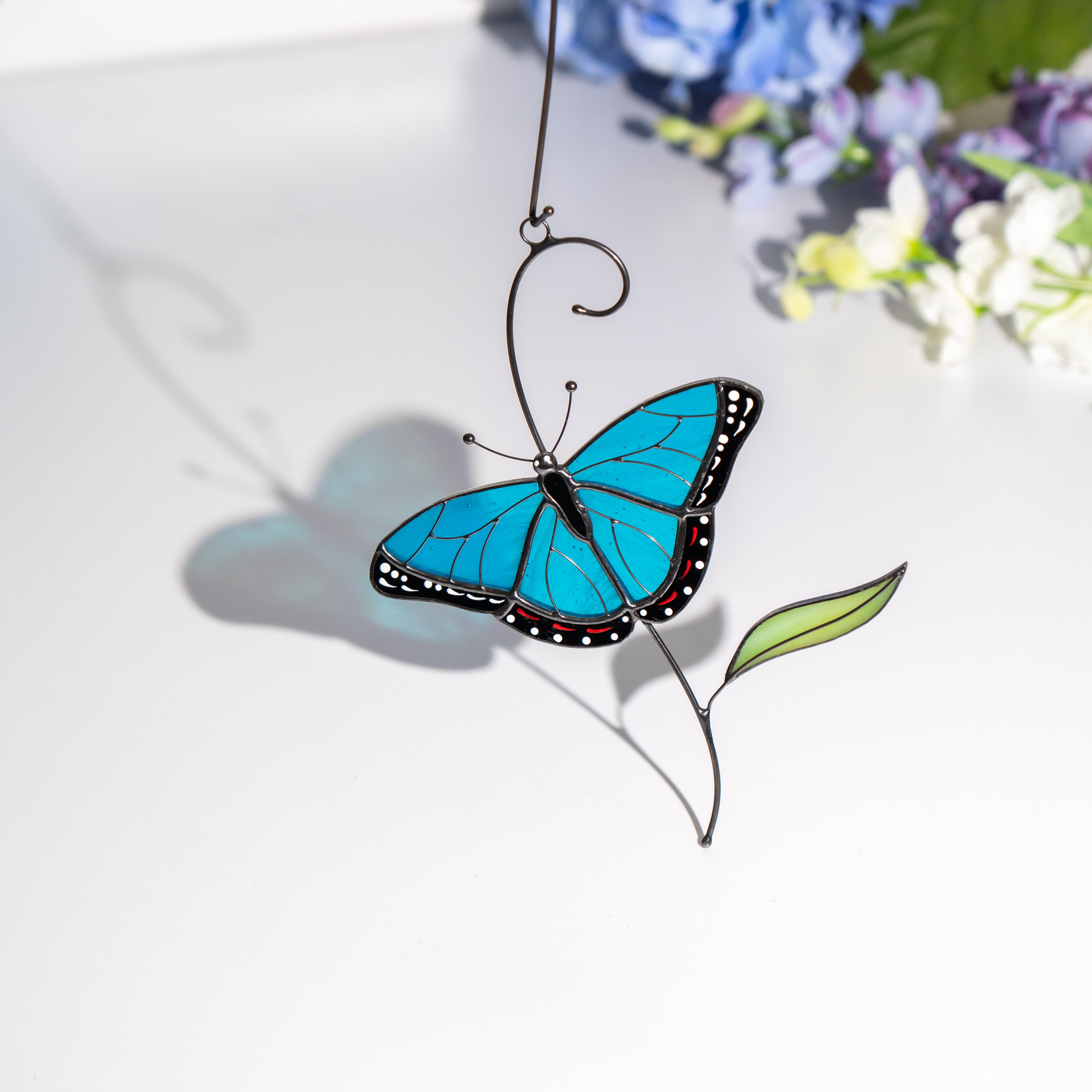 Glass morpho butterfly decor with blue shadow cast on a white surface.