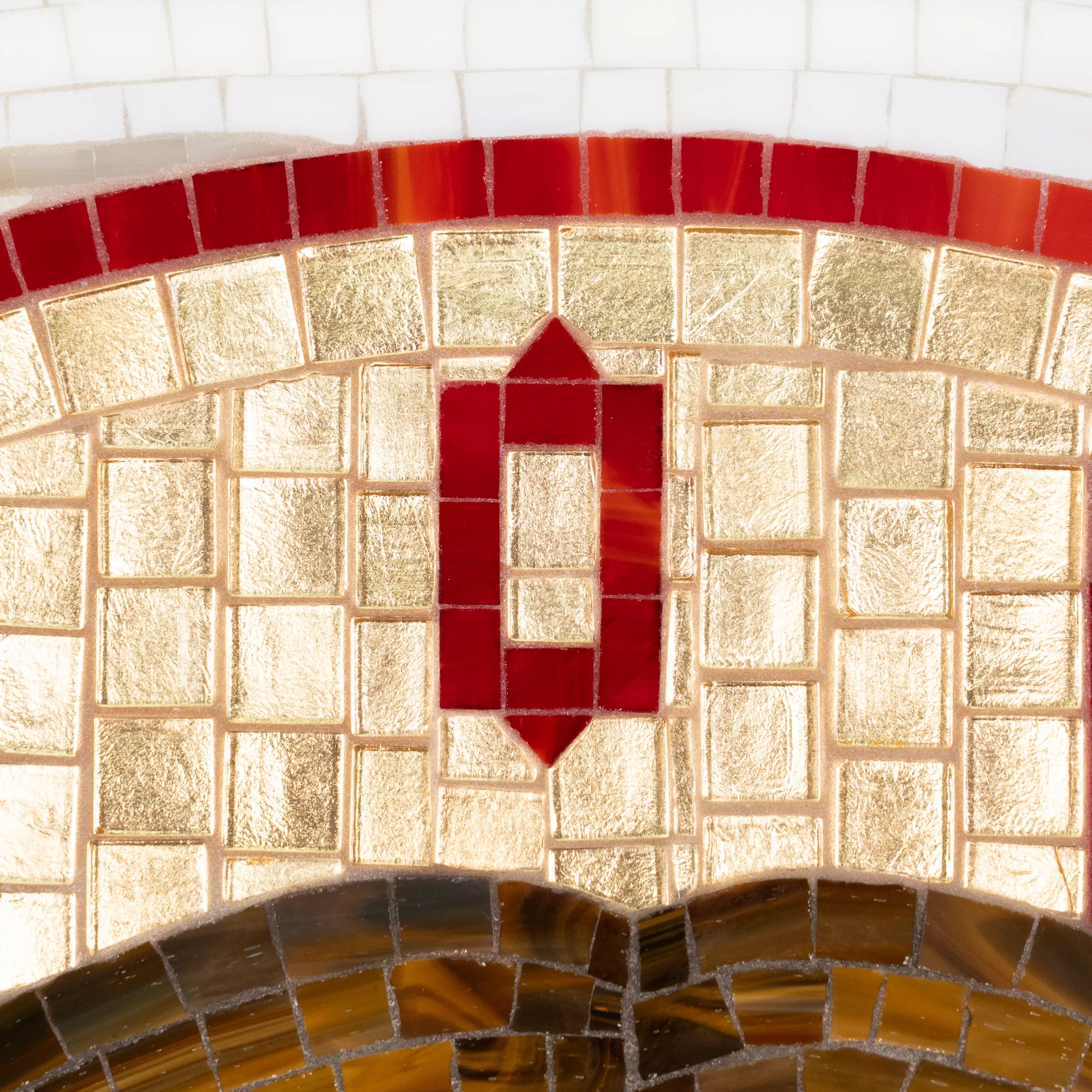 Stained glass mosaic design with red and brown tiles on a tiled wall