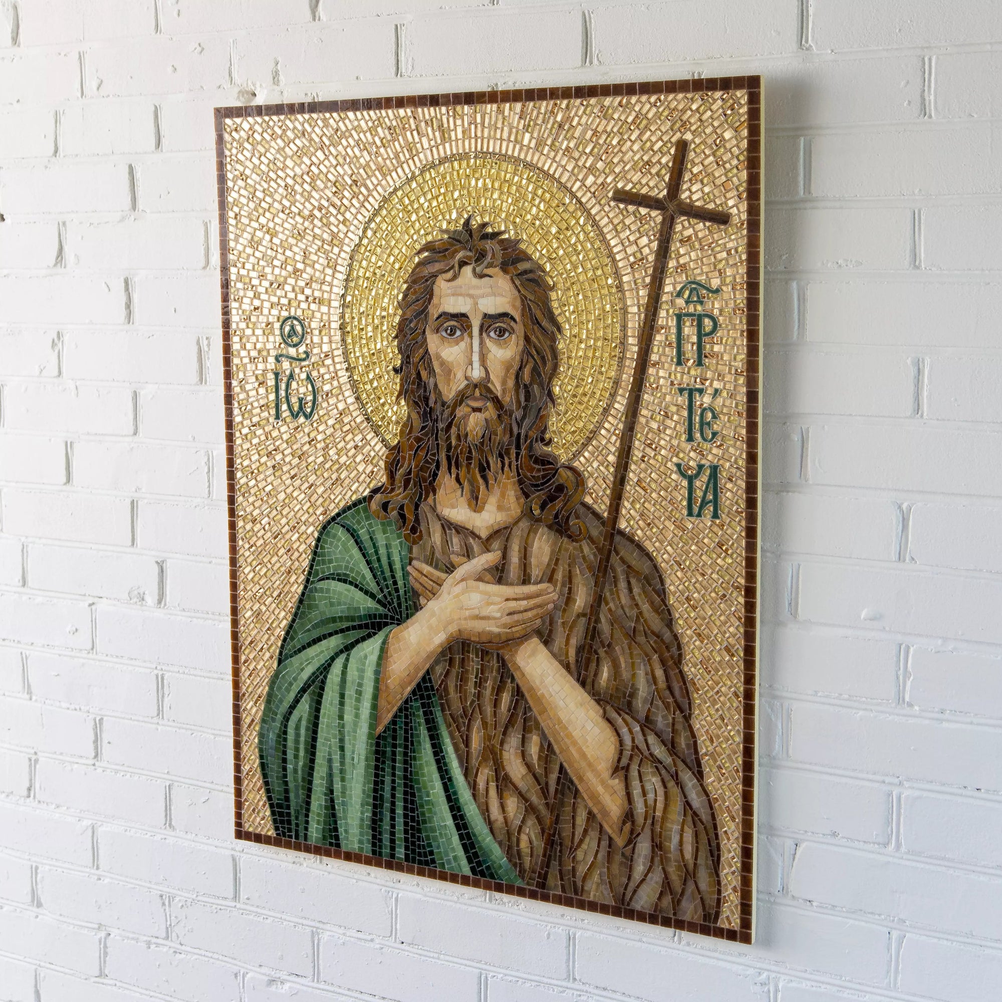 Full mosaic icon of John the Baptist mounted on light wall indoors