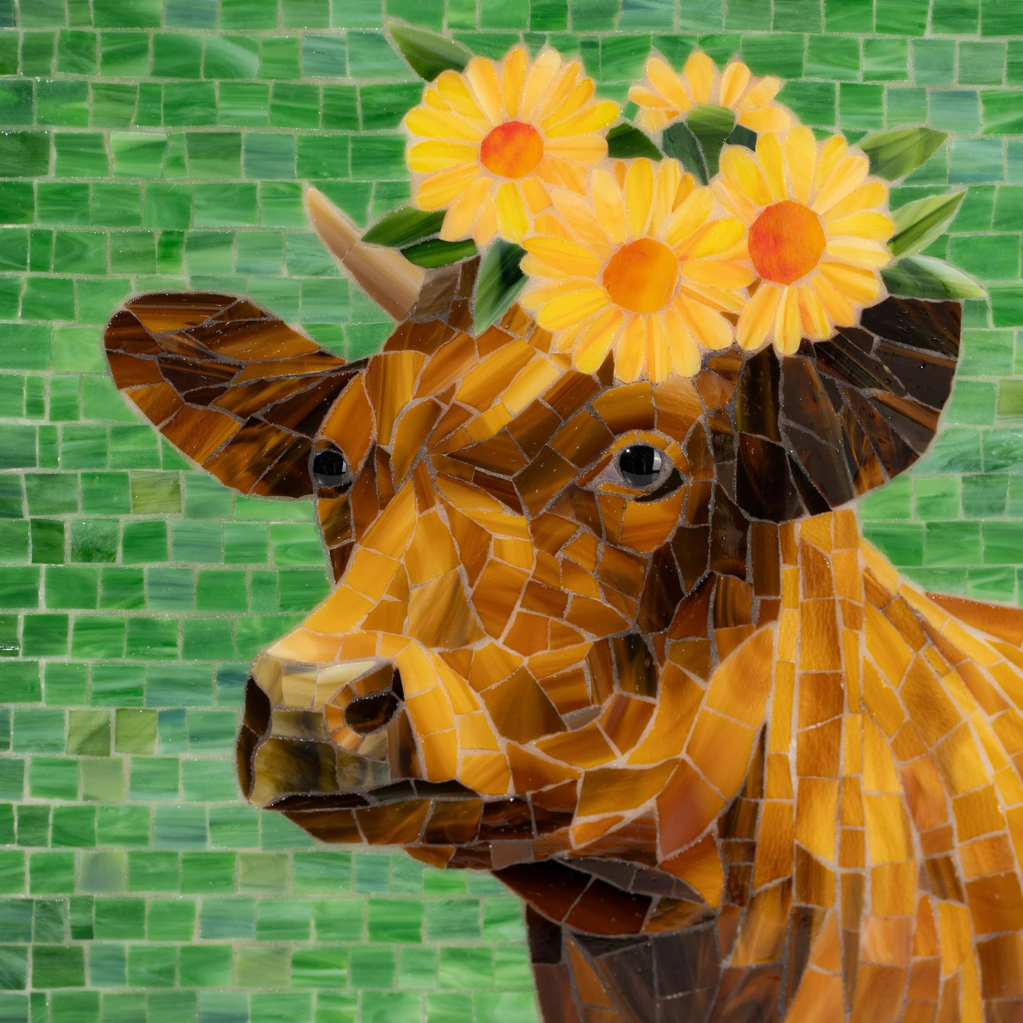 Close-up view of stained glass mosaic of a cow with sunflowers on a green tiled background