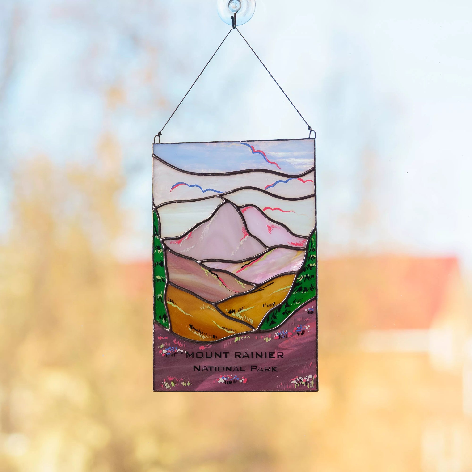 A rectangular stained glass panel featuring the snow-capped Mount Rainier with purple wild lupine flowers in the foreground.
