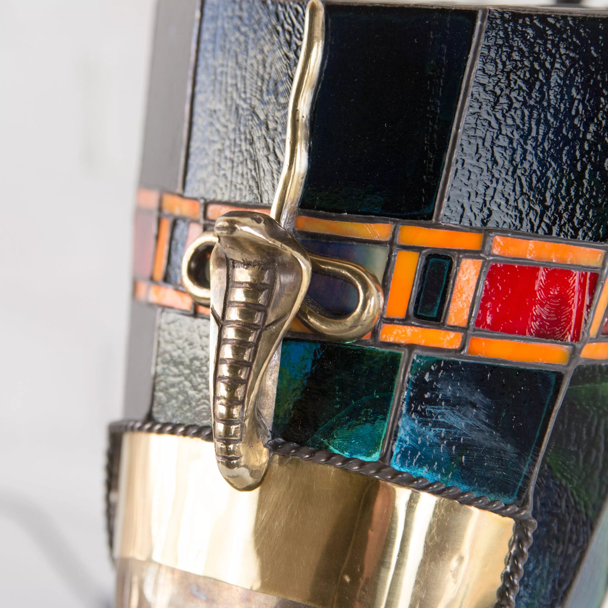 Top section of stained glass lamp showing geometric glass pattern and bronze finial details