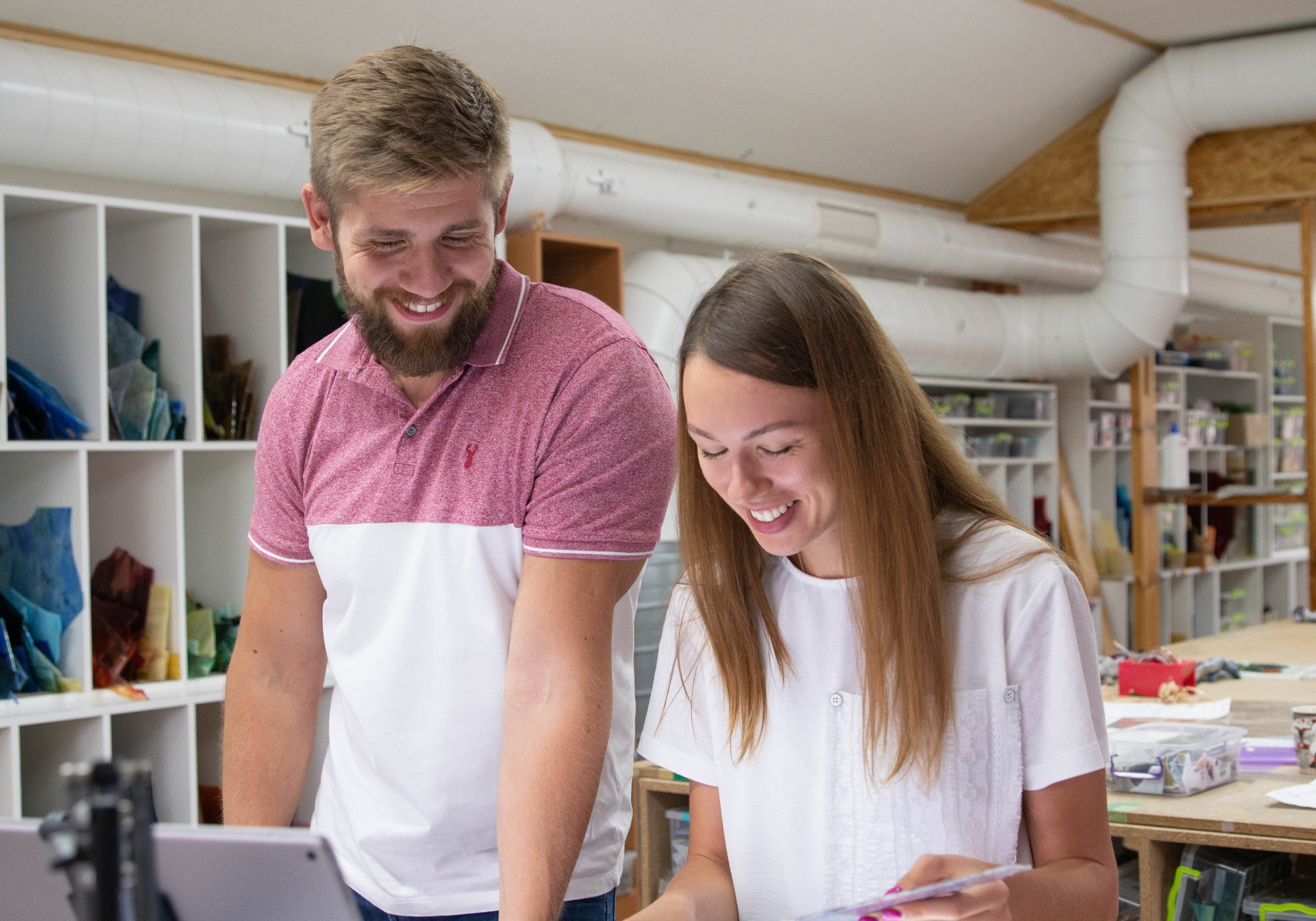 Man and woman smiling while working together in a creative workshop