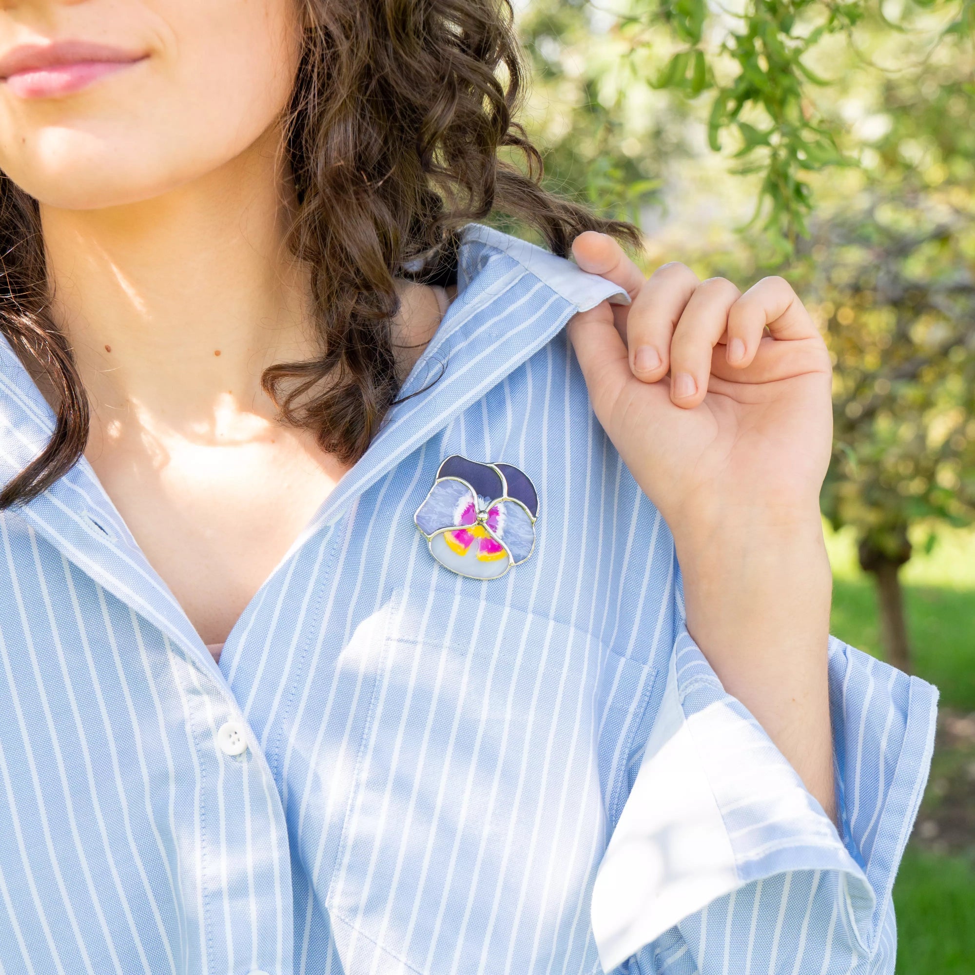 Purple pansy brooch on a blue stripped shirt