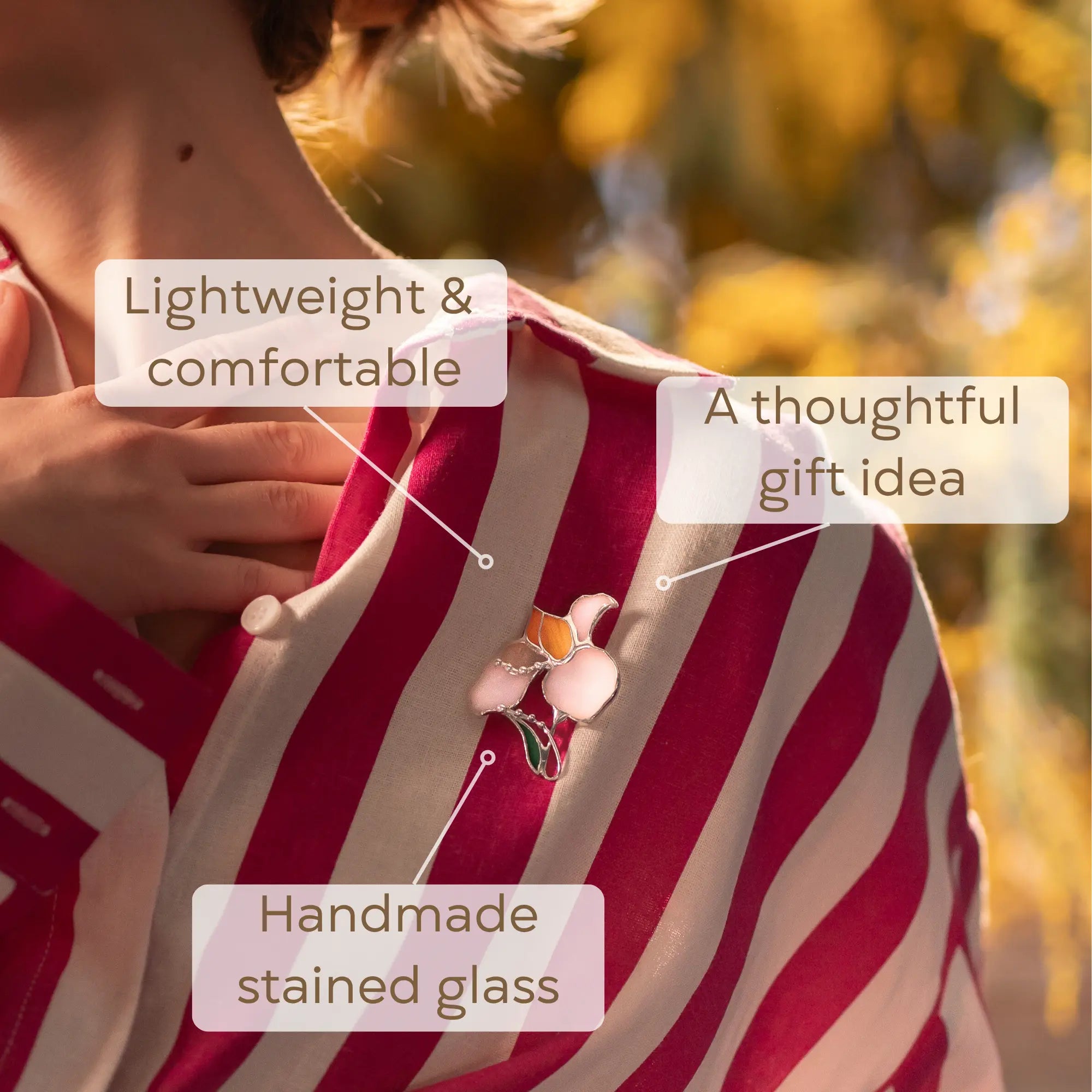 Person wearing a pink and white striped shirt with white iris stained glass brooch