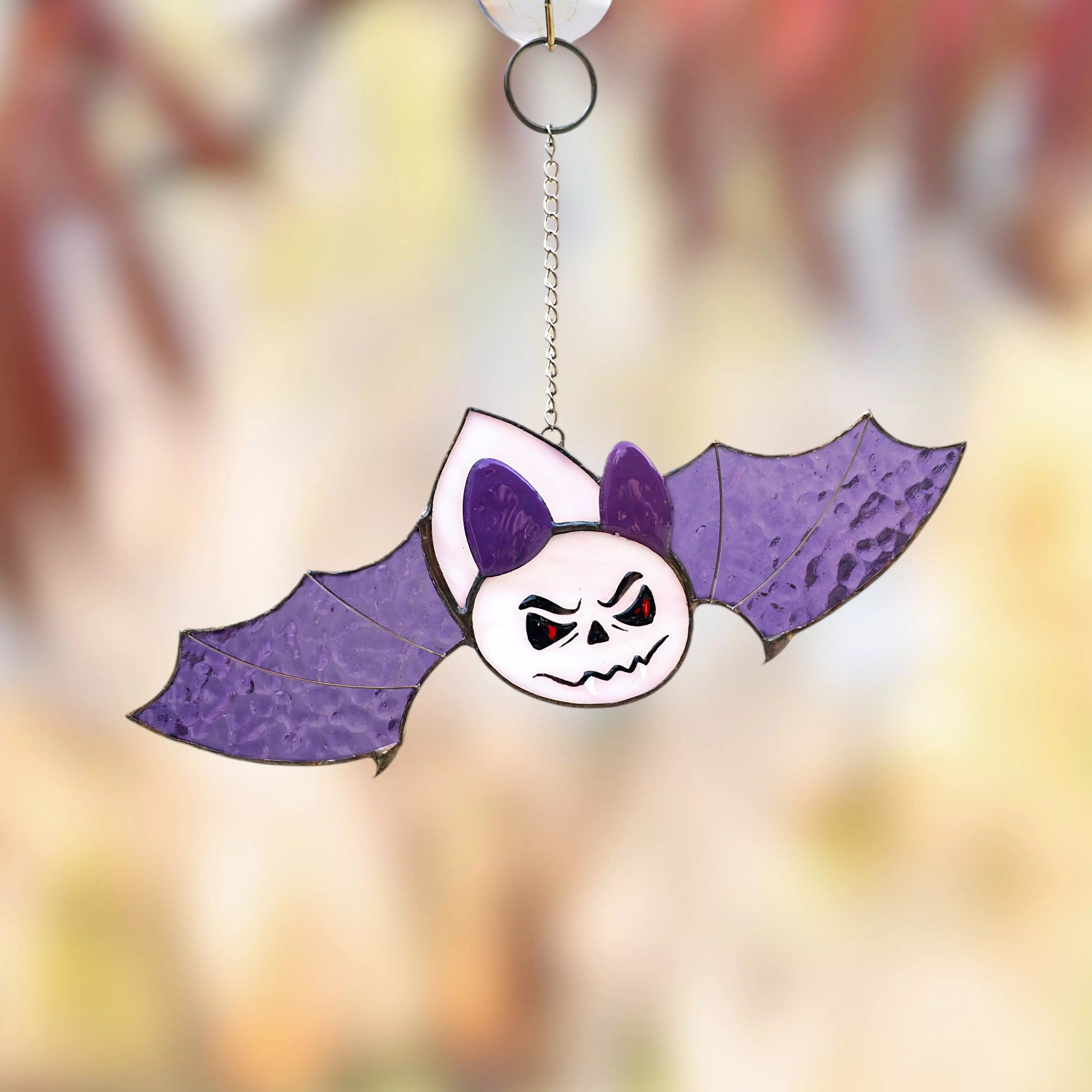 Spooky stained glass bat with purple wings hanging on suction cup by window