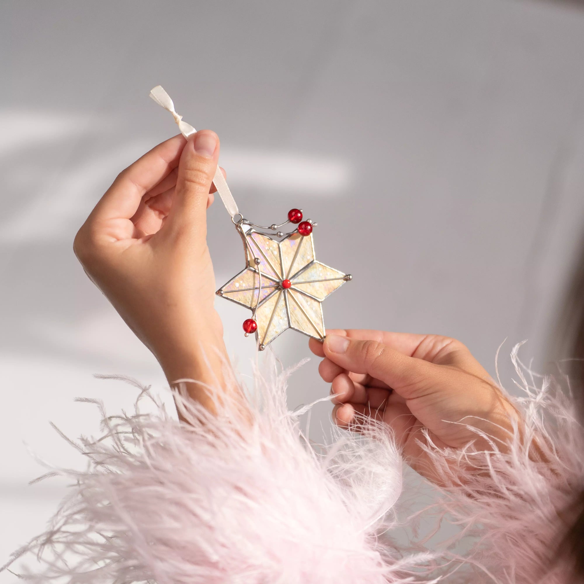 Close-up of stained glass star ornament with red accents hanging on a Christmas tree branch