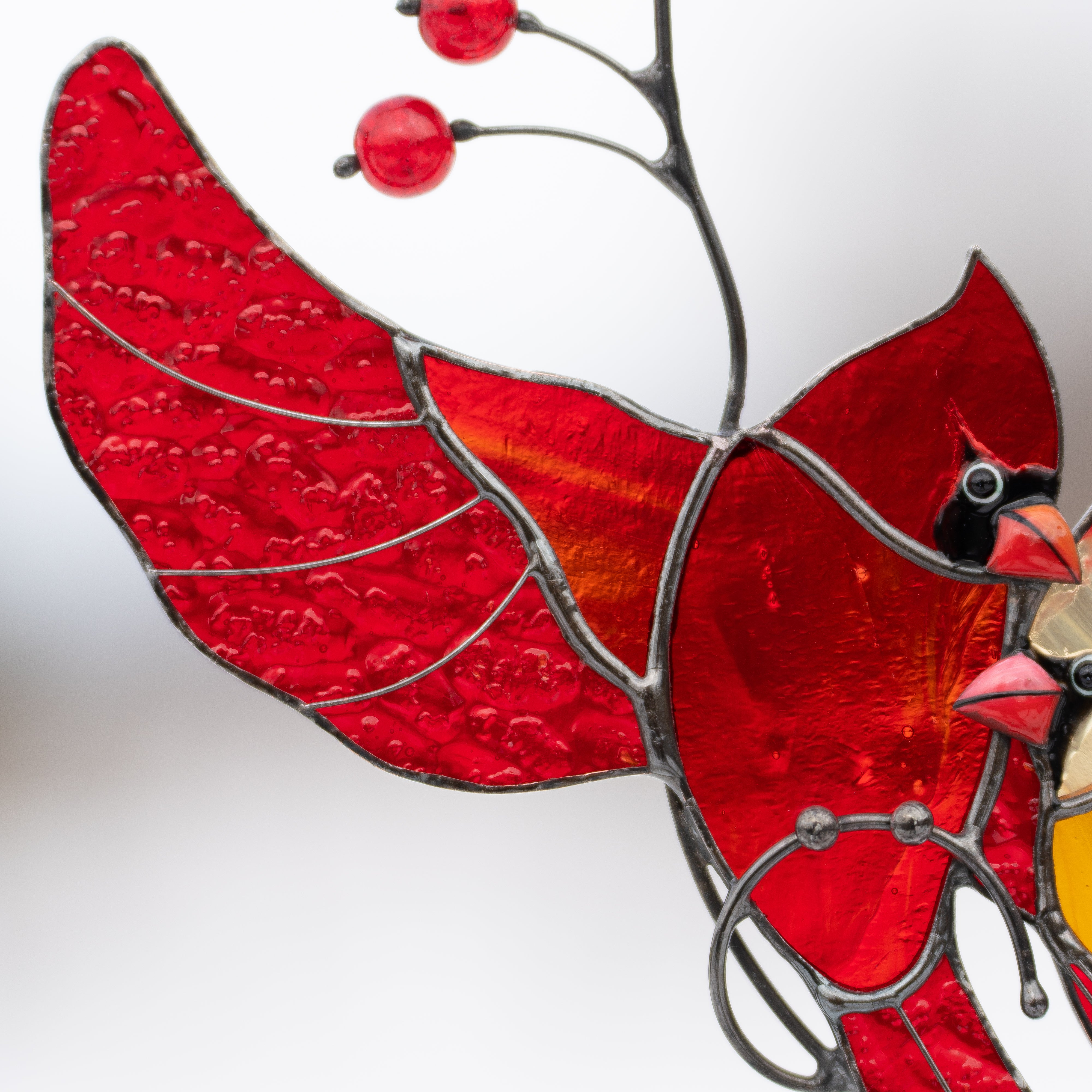 Detailed stained glass cardinal wing with red beads and vivid handcrafted glass.