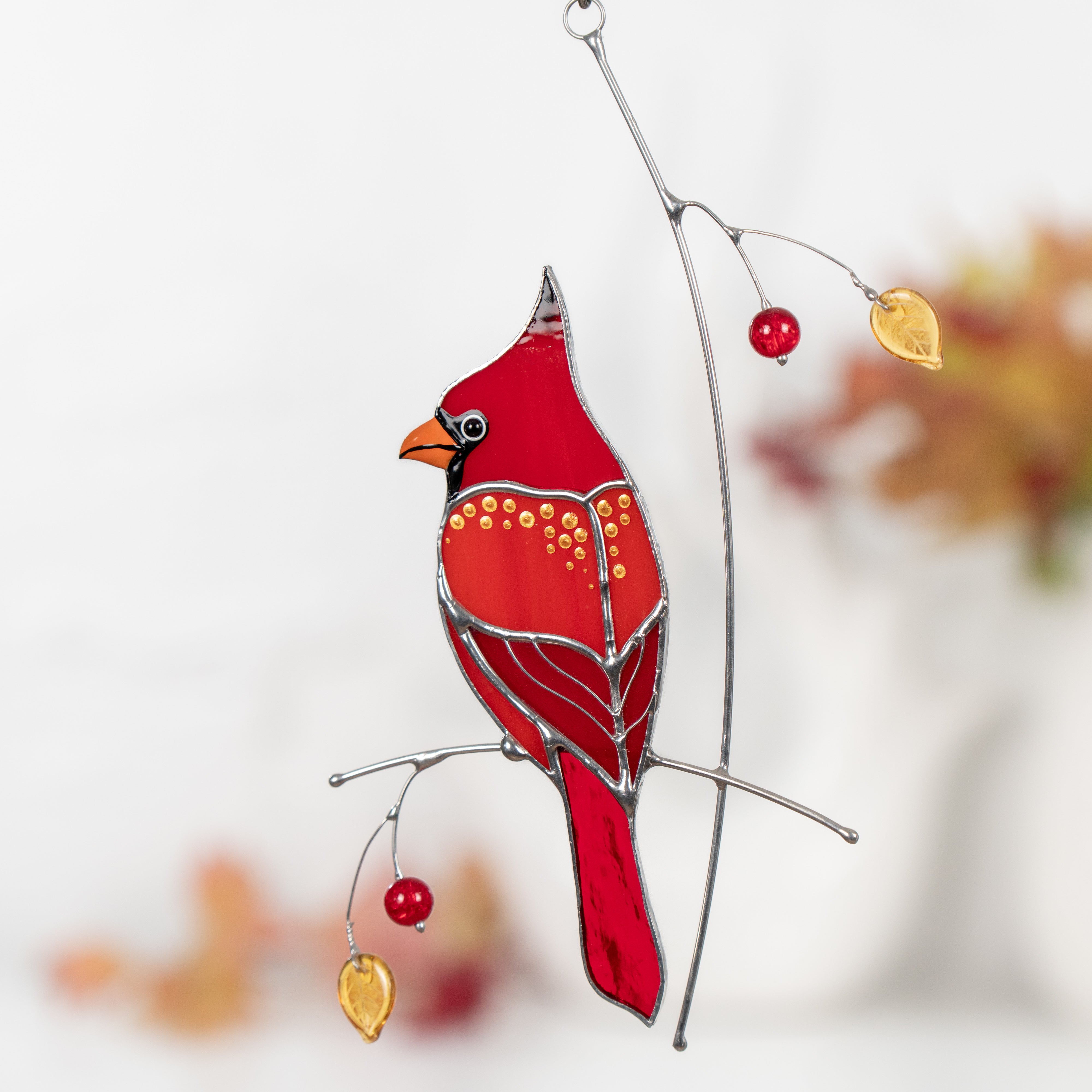 Stained glass cardinal features golden accents and delicate leaves for elegant holiday-themed decor.