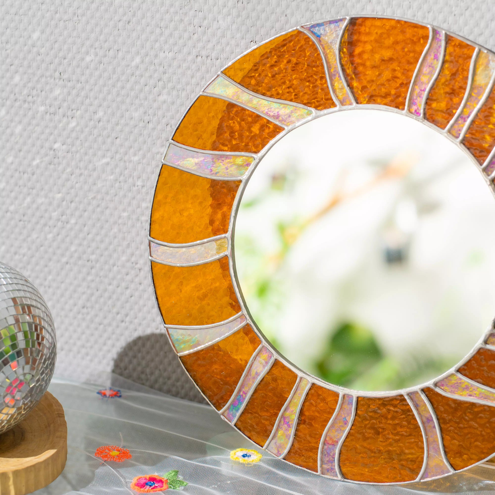 Round mirror with a decorative orange frame on a textured wall background
