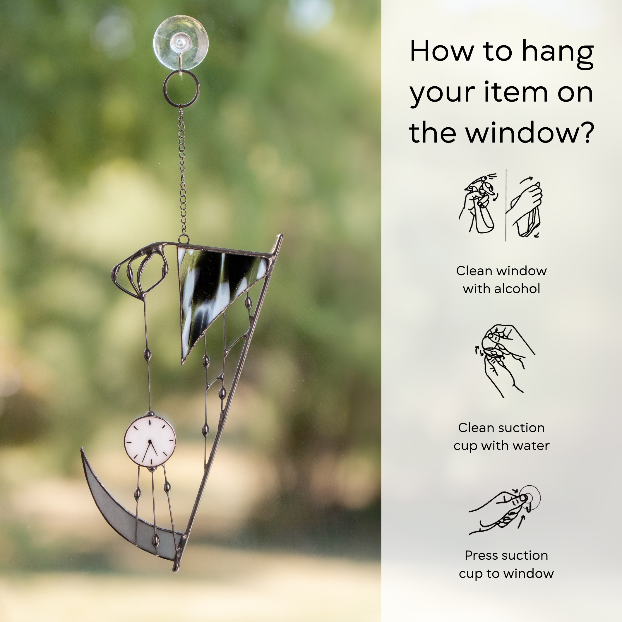 “Hand of Death” suncatcher hanging on window with suction cup, featuring black-and-white stained glass and clock with instruction beside: clean window and suction cup, press a cup to the surface.