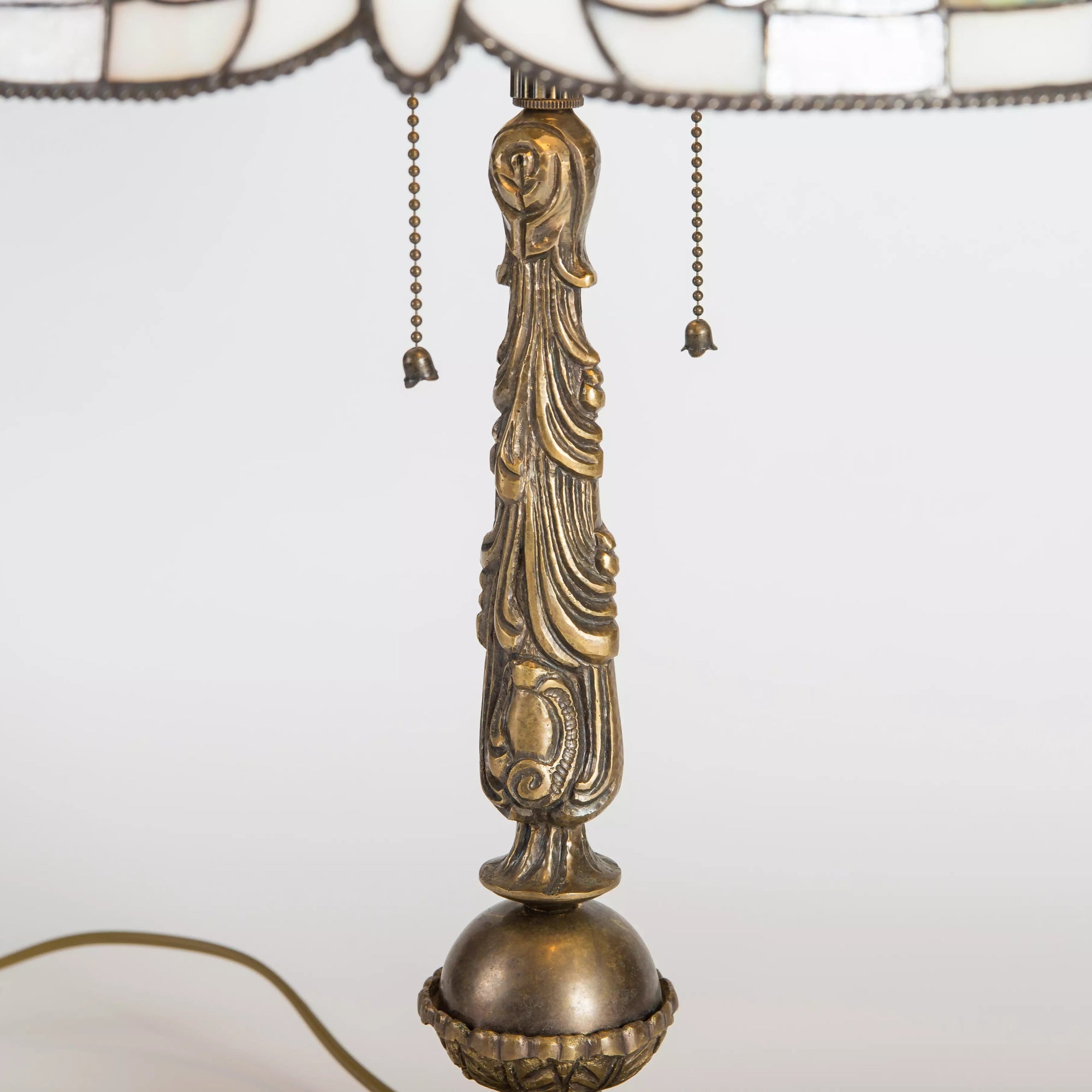 Close-up of the vertical stand of the lamp with ornate detailing in bronze tone