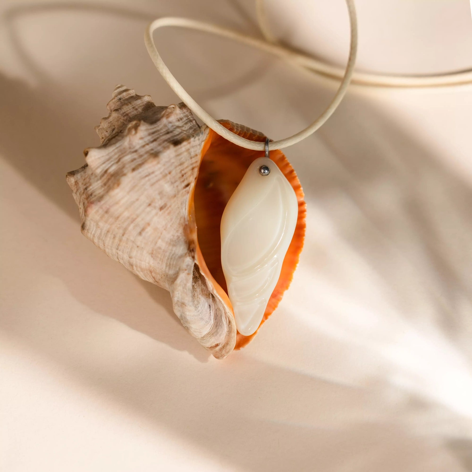 Shell with a stained glass pendant on a beige background