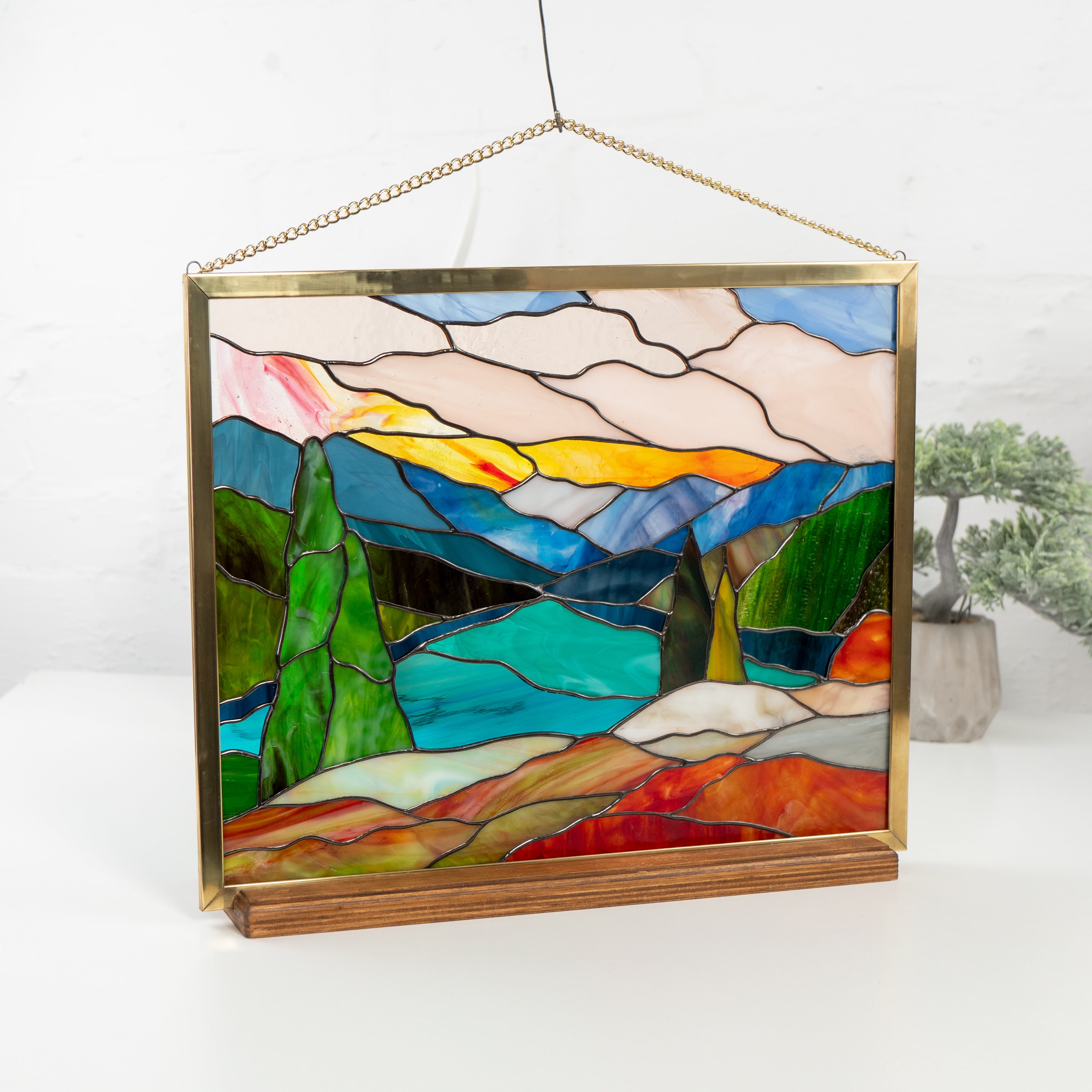Angled image of Mount Rainier stained glass panel on display with mountains, trees, and lake scene