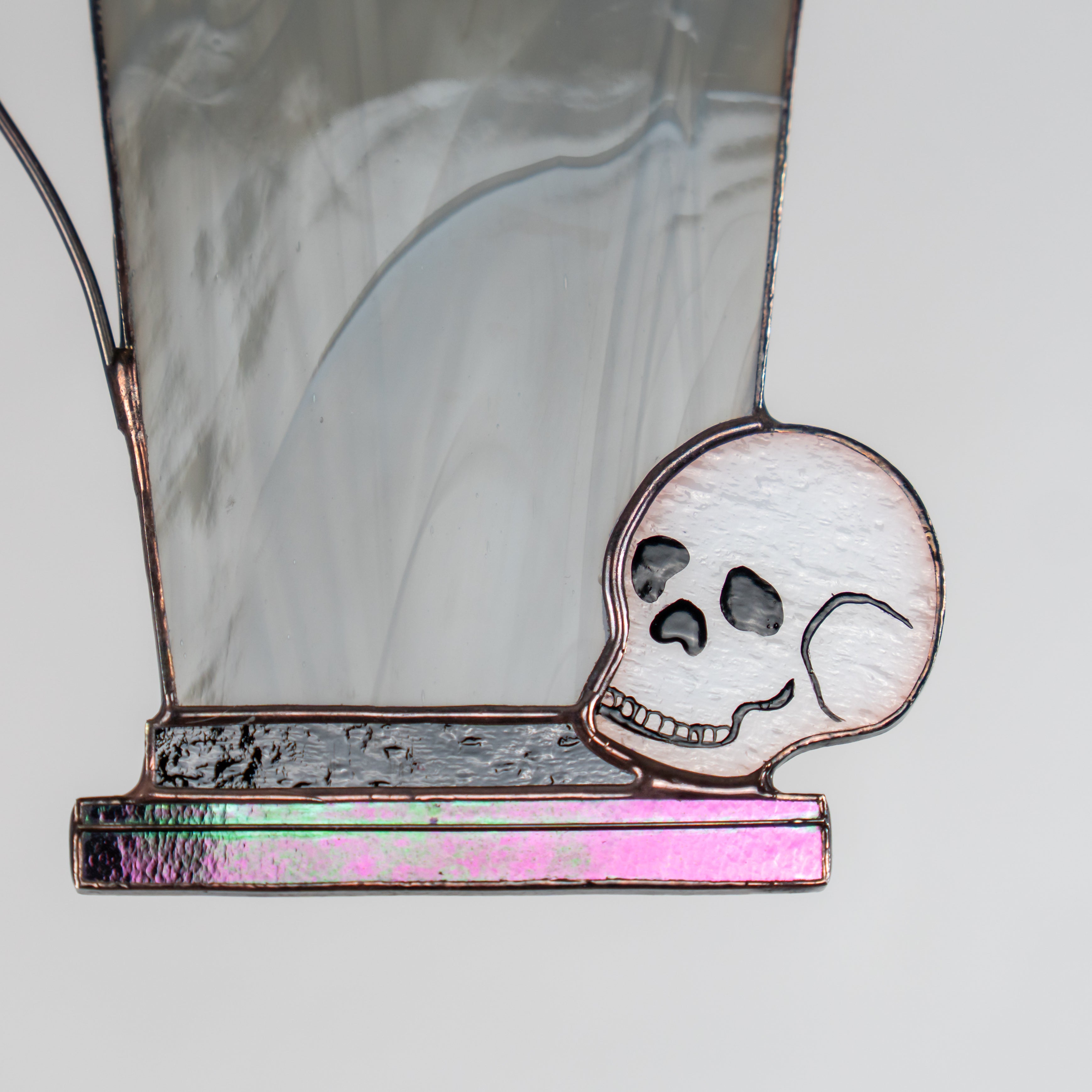 Close-up of the skull and iridescent purple glass base at bottom of stained glass tombstone decor.
