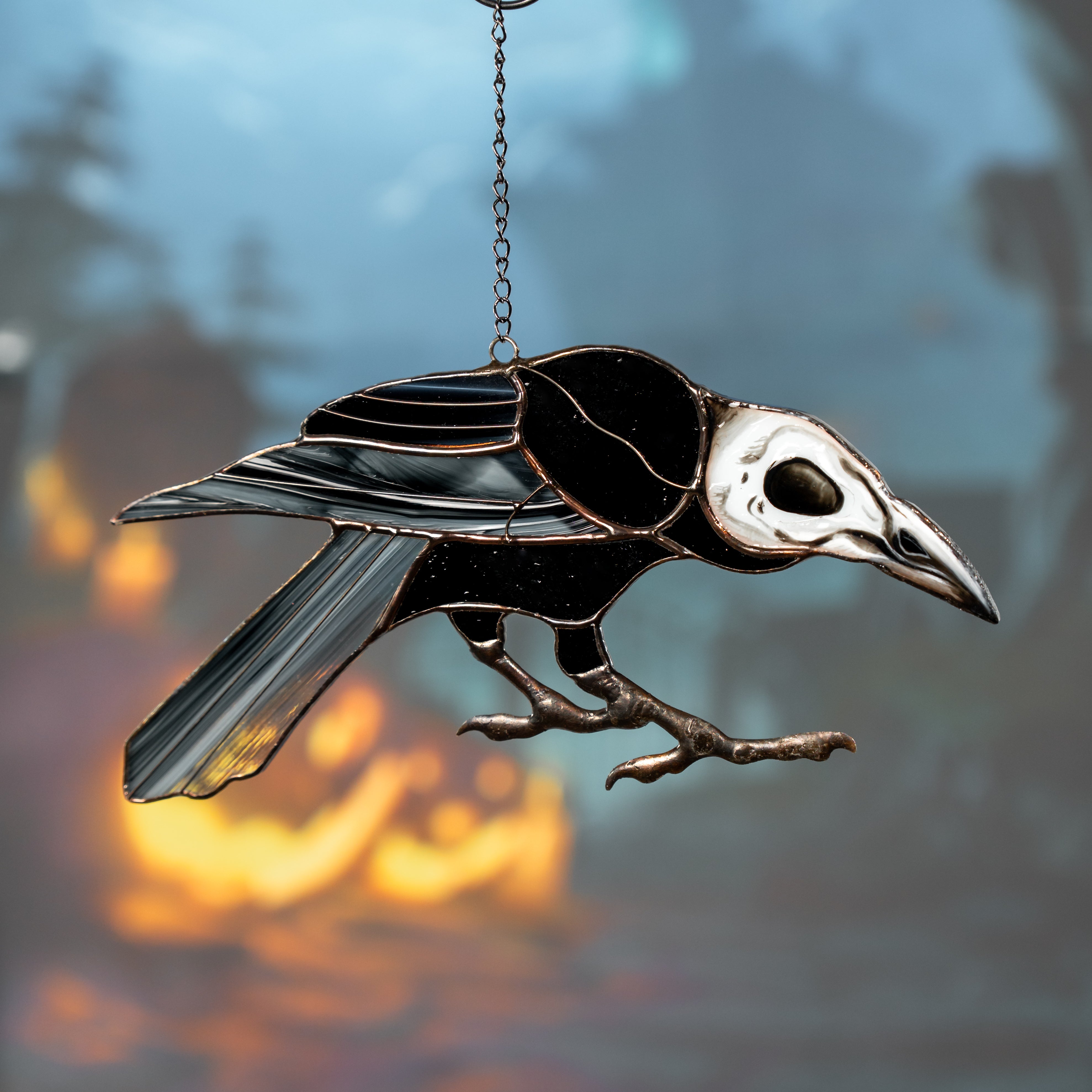 Stained glass raven with bone skull and dark feathers set against a glowing flame and shadowy tree background.