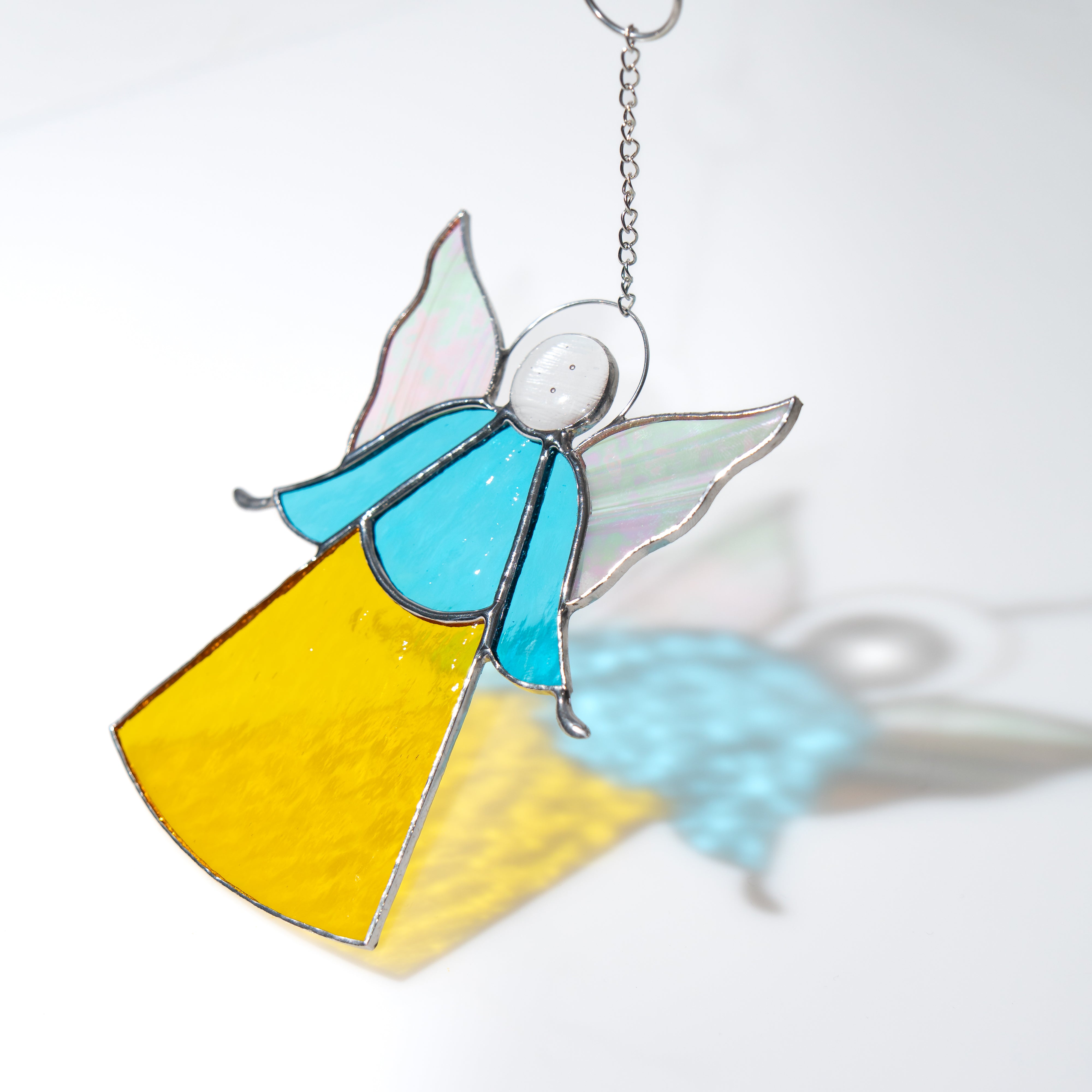 Angel with iriscendent wings stained glass suncatcher casting a soft shadow