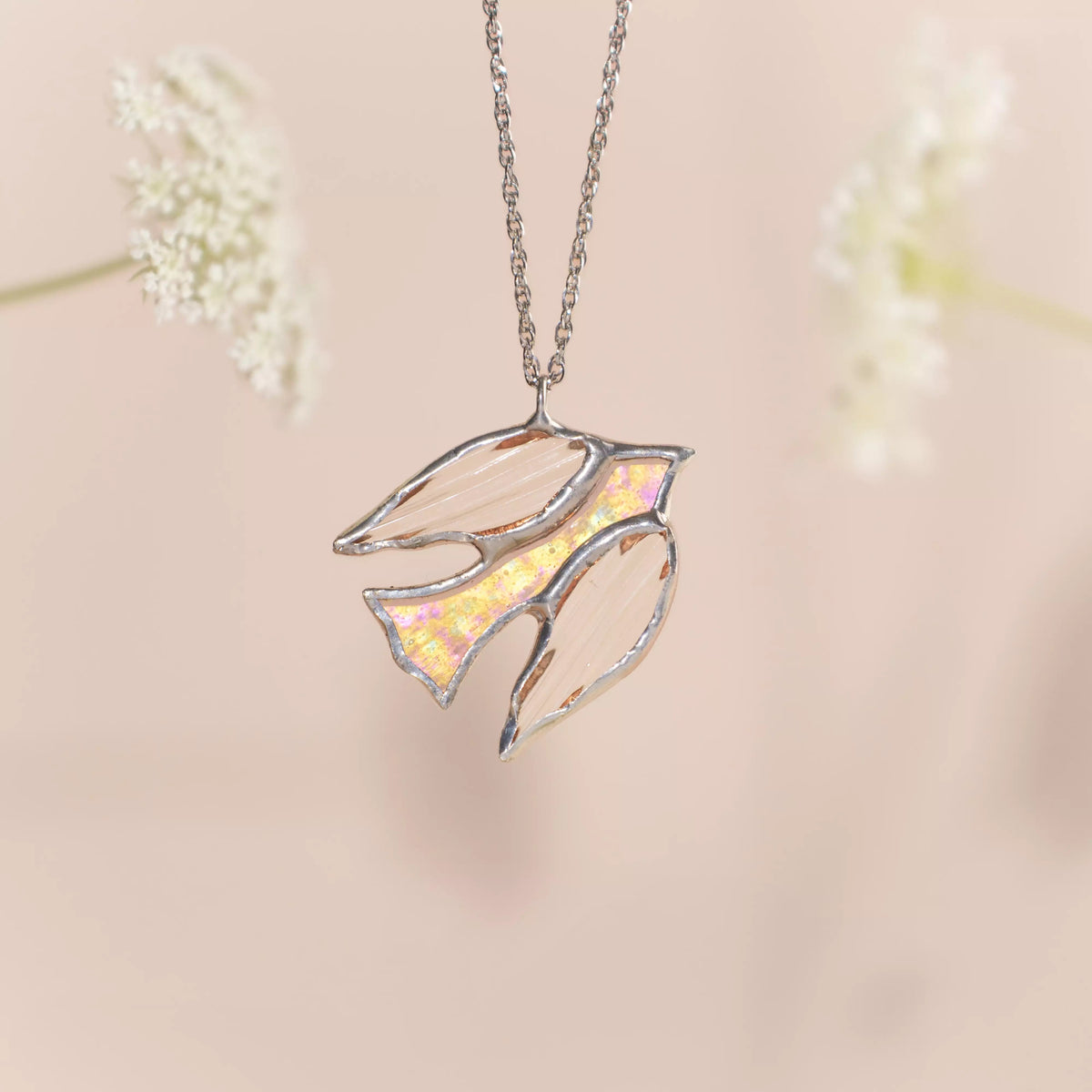 Stained glass clear bird pendant necklace on a soft pink background