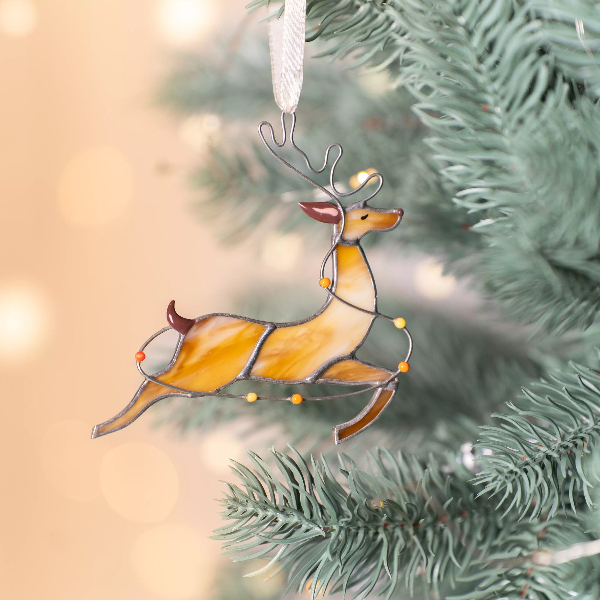Stained glass reindeer with colorful lights hanging on a Christmas tree