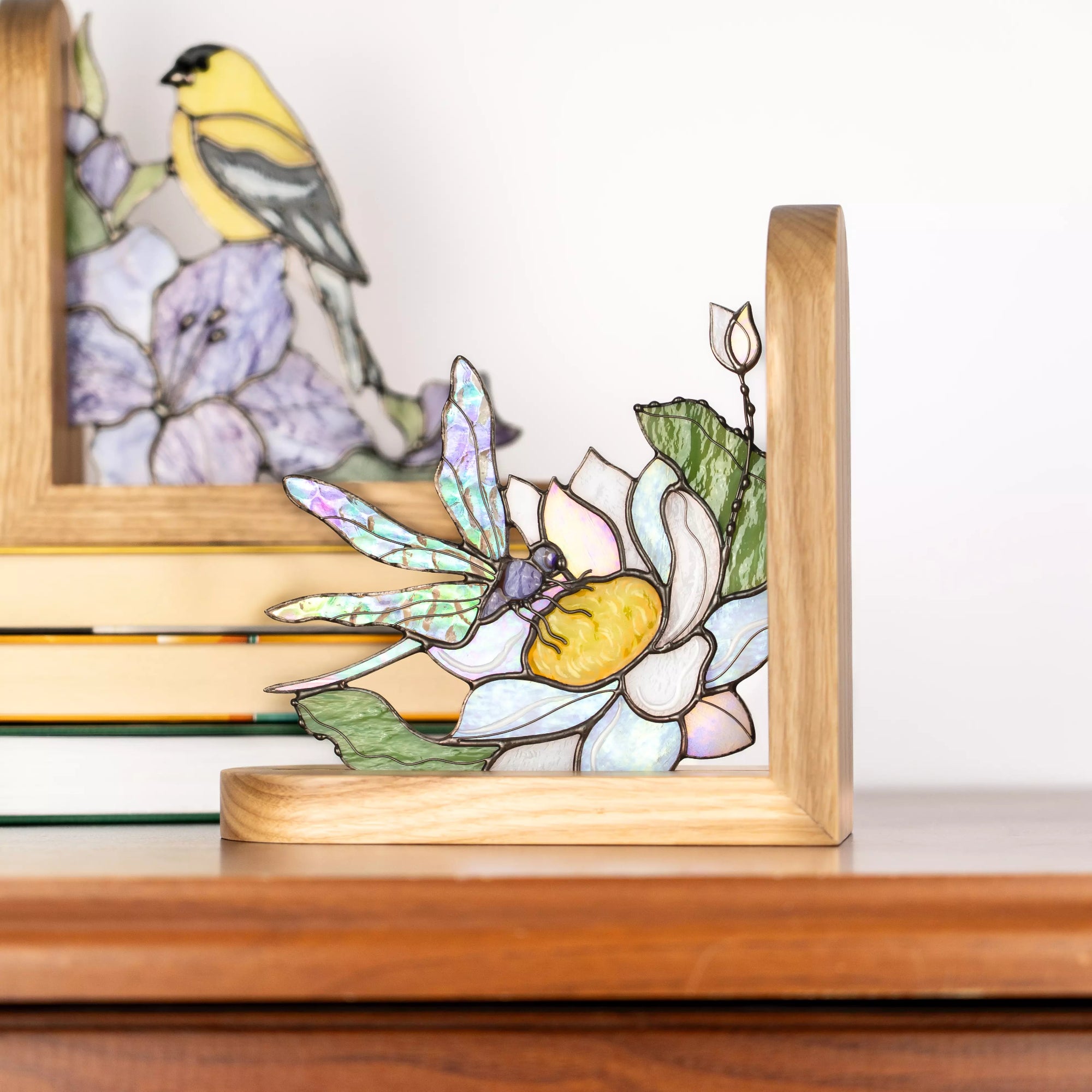 Handmade stained glass dragonfly panel standing in a wooden base on a table.