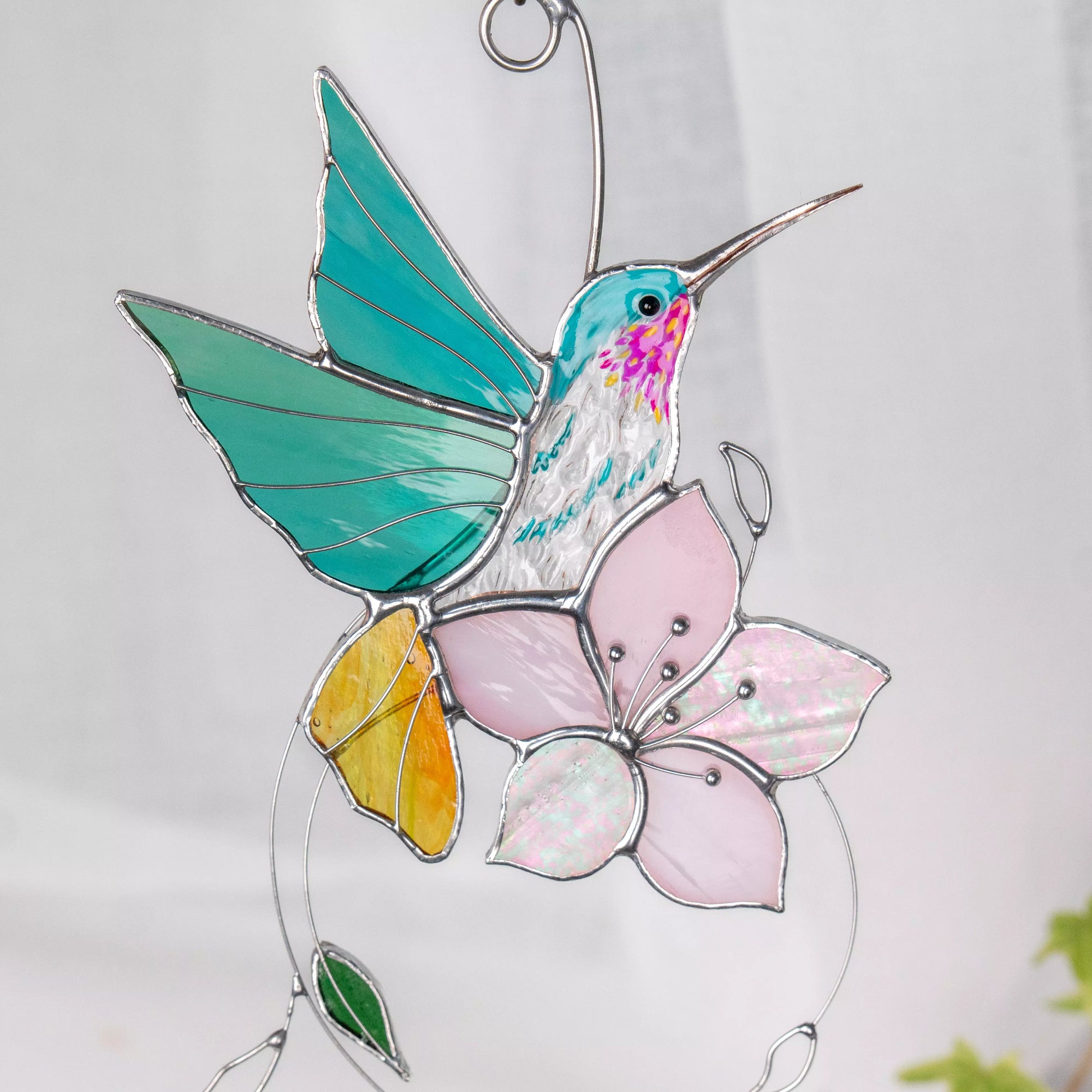 Stained glass blue hummingbird and flower suncatcher on a white background
