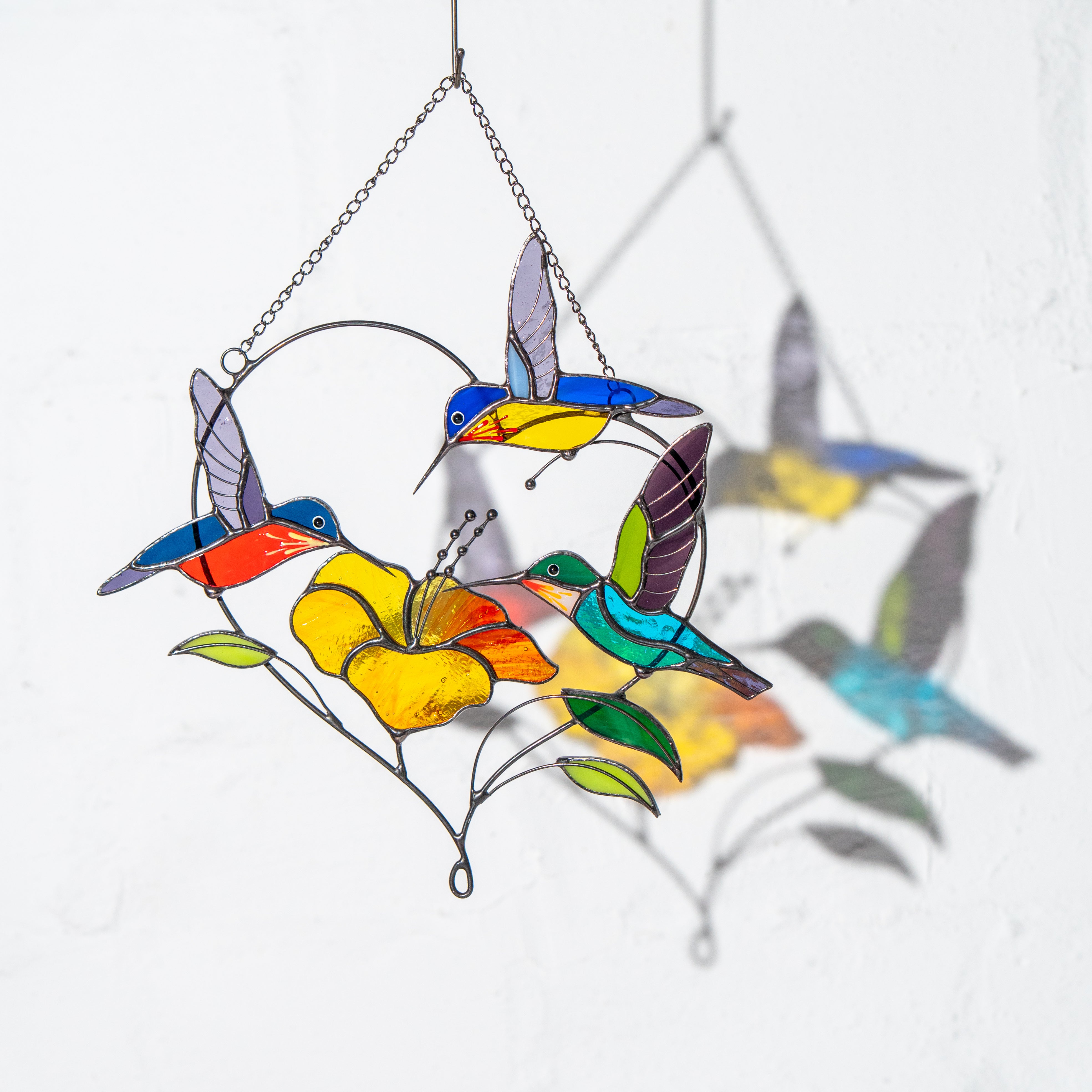 Full stained glass design with three birds and flower casting vibrant reflections on a white background.