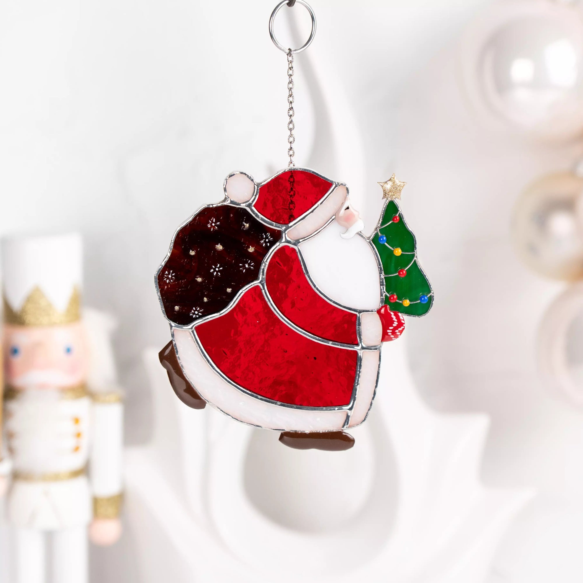 Stained glass suncatcher of Santa Claus holding a Christmas tree on a white background