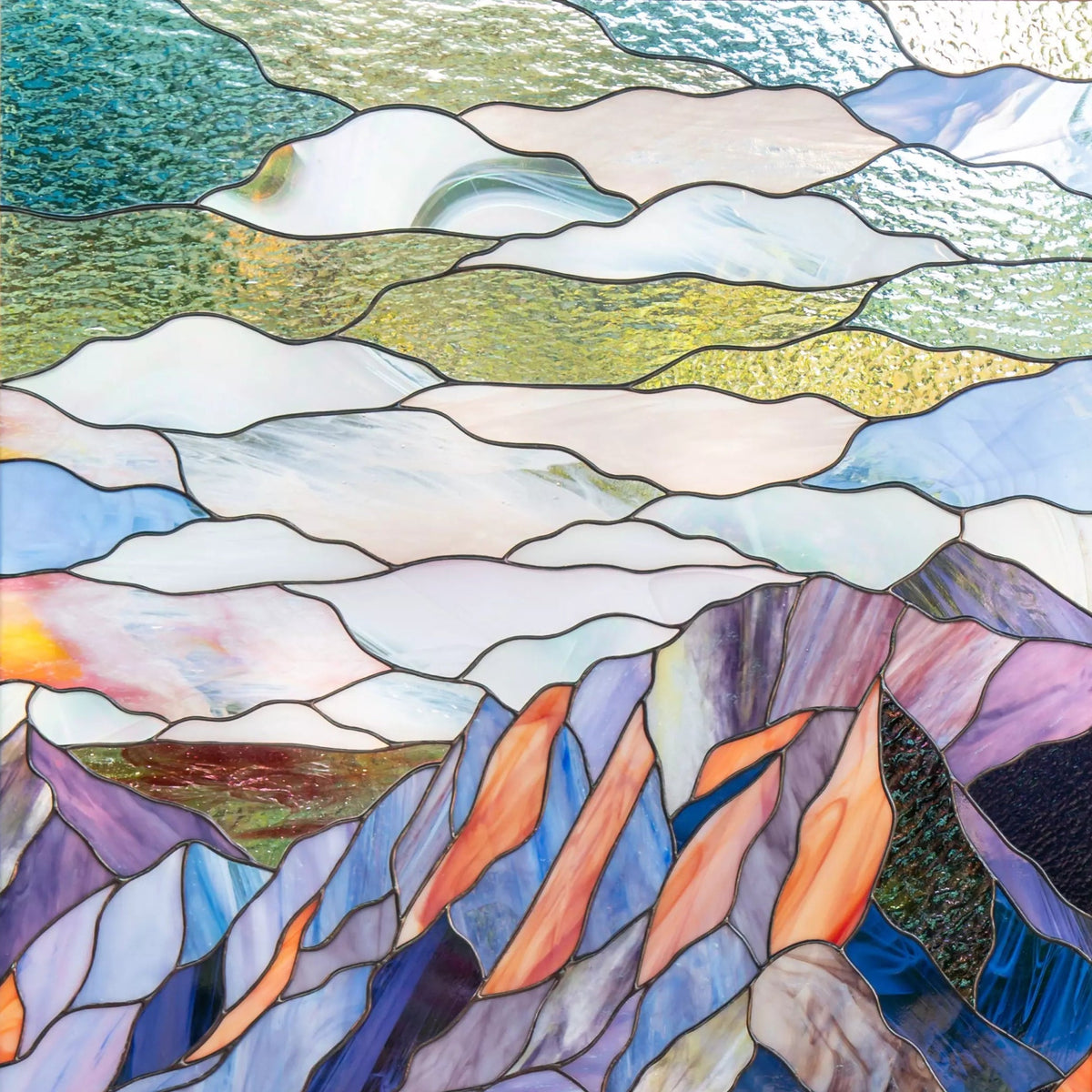 Stained glass panel of a mountain Flatirons landscape held in front of greenery
