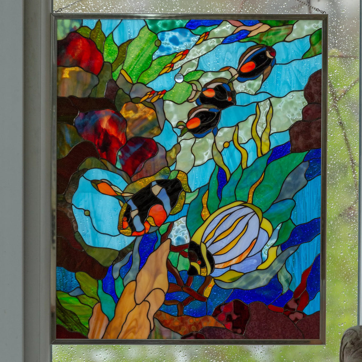 Custom stained glass panel with fish design hanging on a window