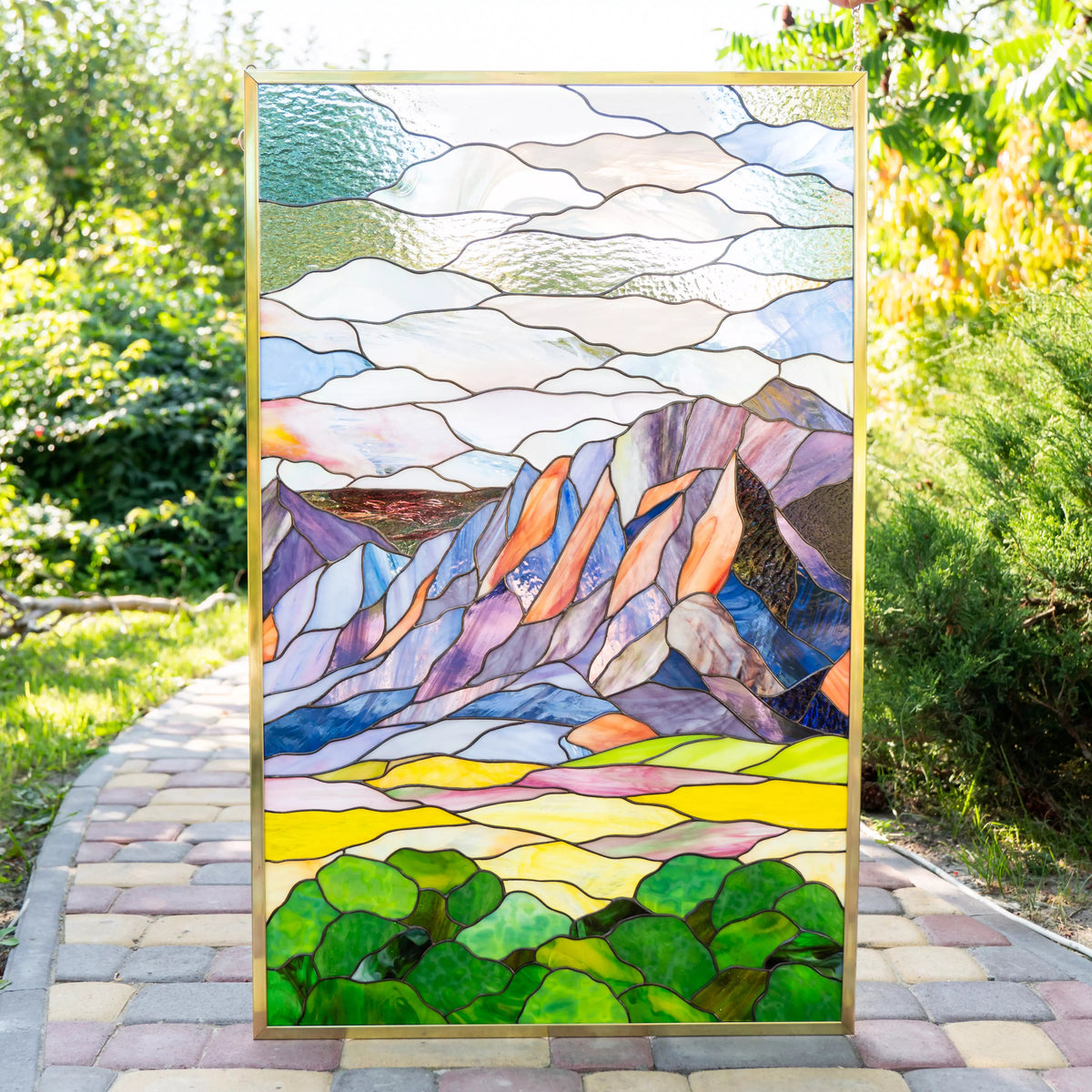 Custom stained glass panel with mountain Flatirons landscape in a garden setting