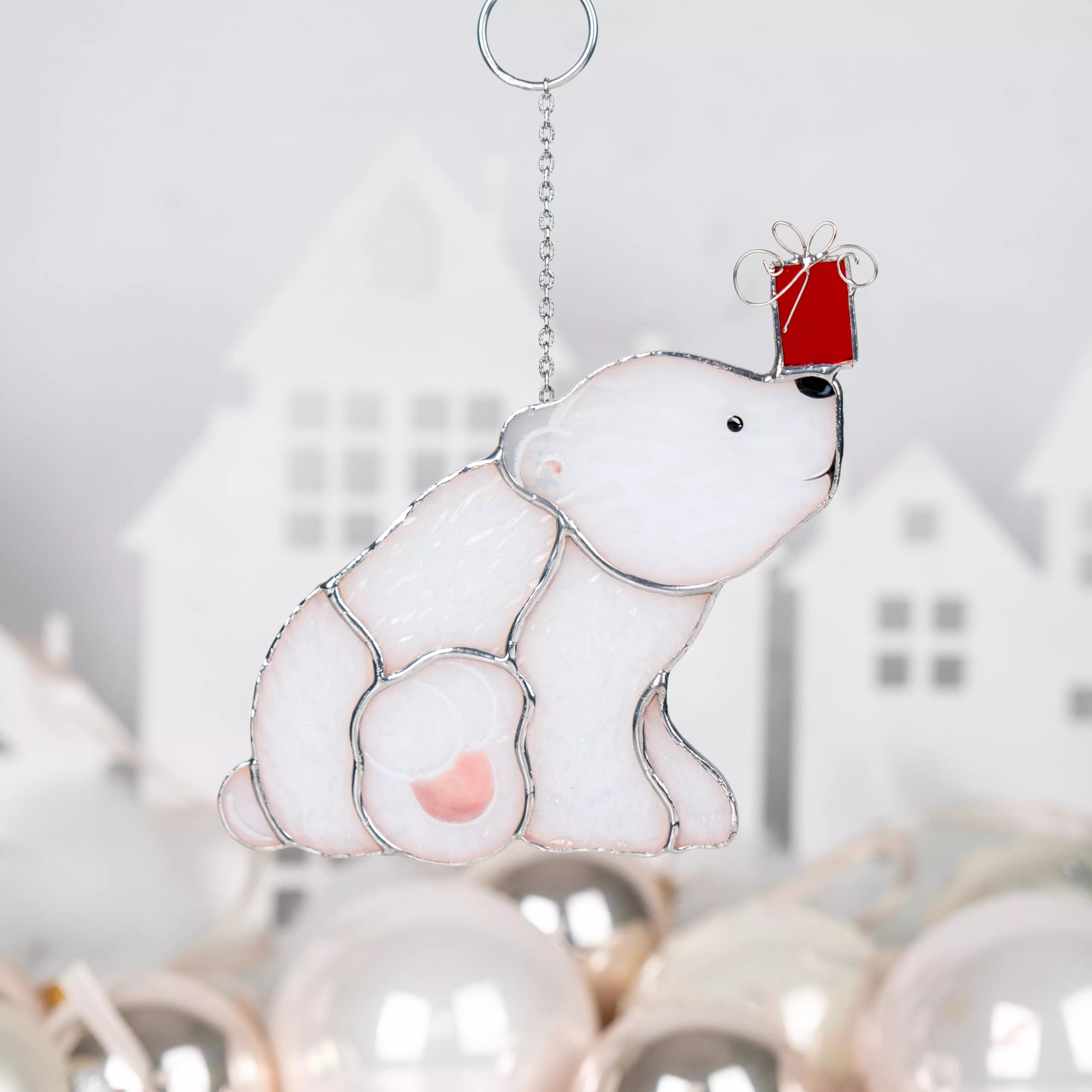 Stained glass window hanging polar bear with a red Christmas gift