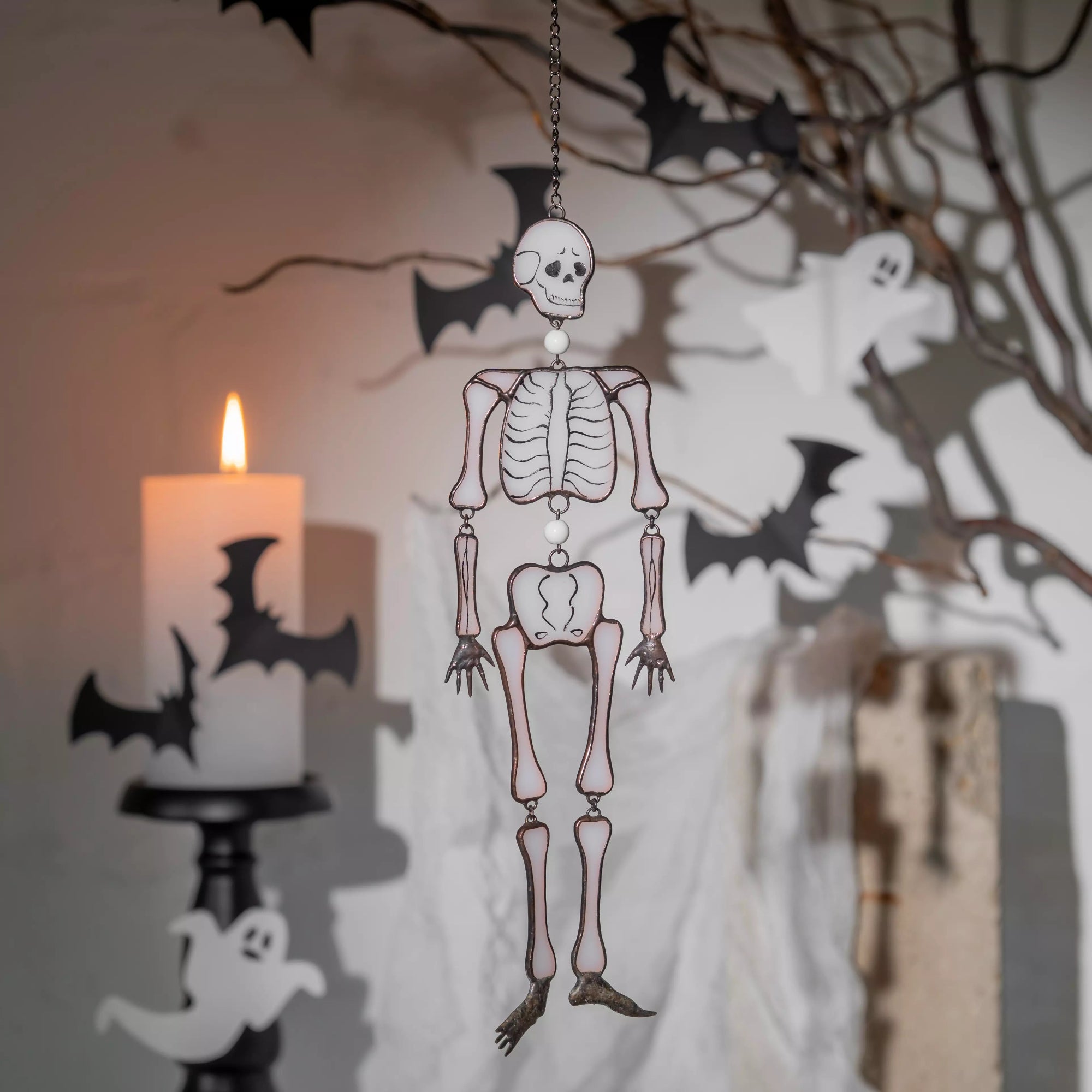 Halloween-themed interior scene with glass skeleton, bats, and candle