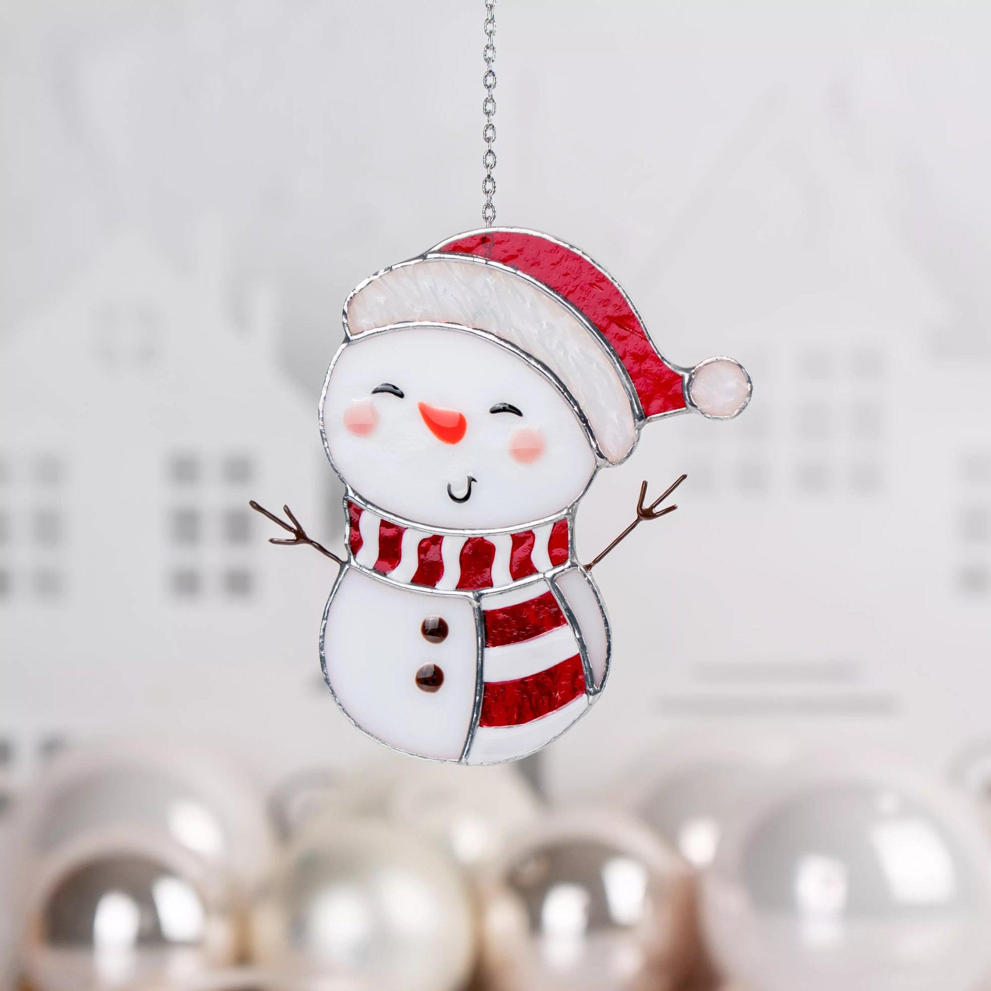 Stained glass suncatcher snowman with a red hat and scarf on a blurred background