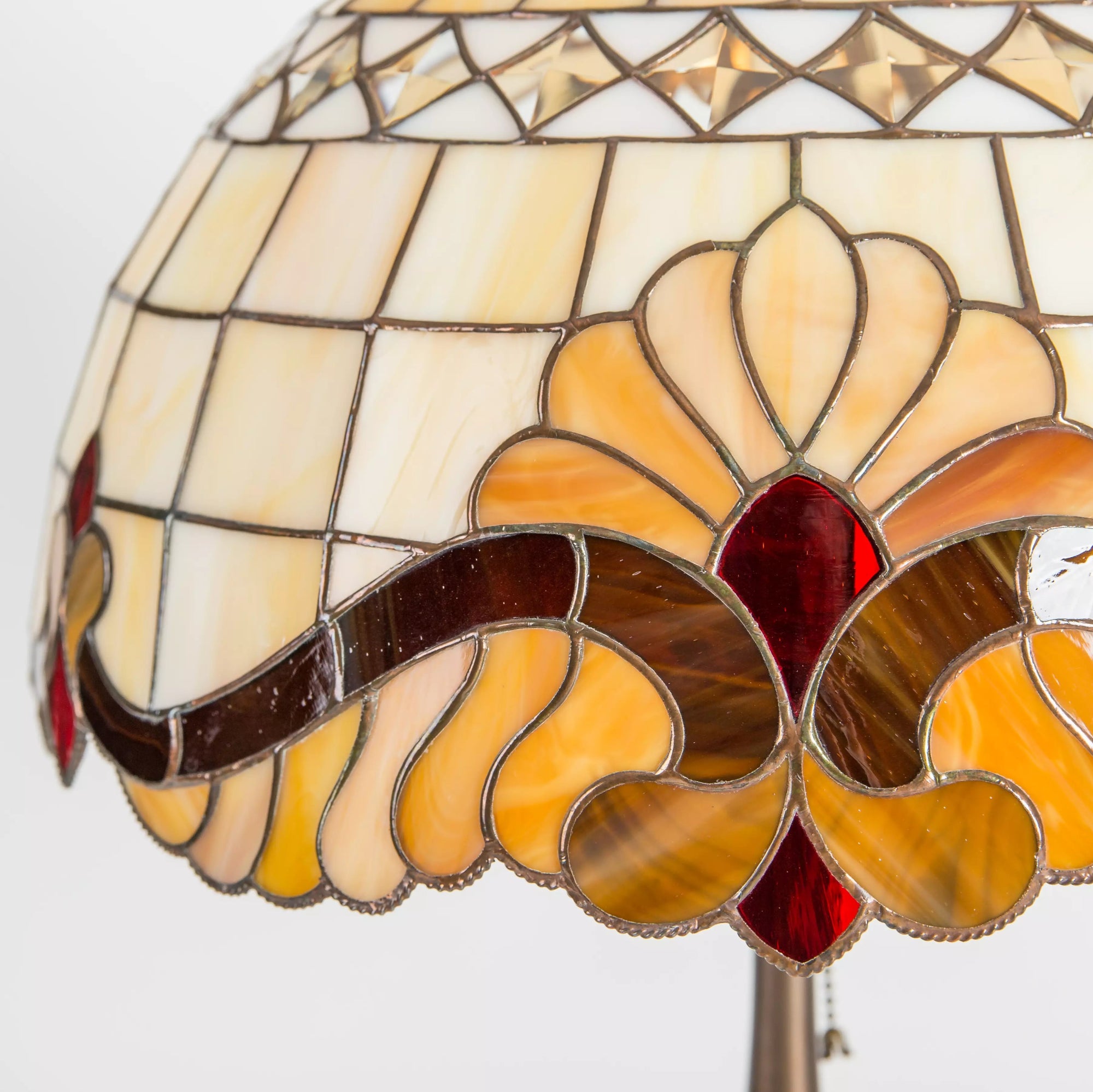 Close-up of Tiffany-style lampshade with red, amber, and cream stained glass floral design