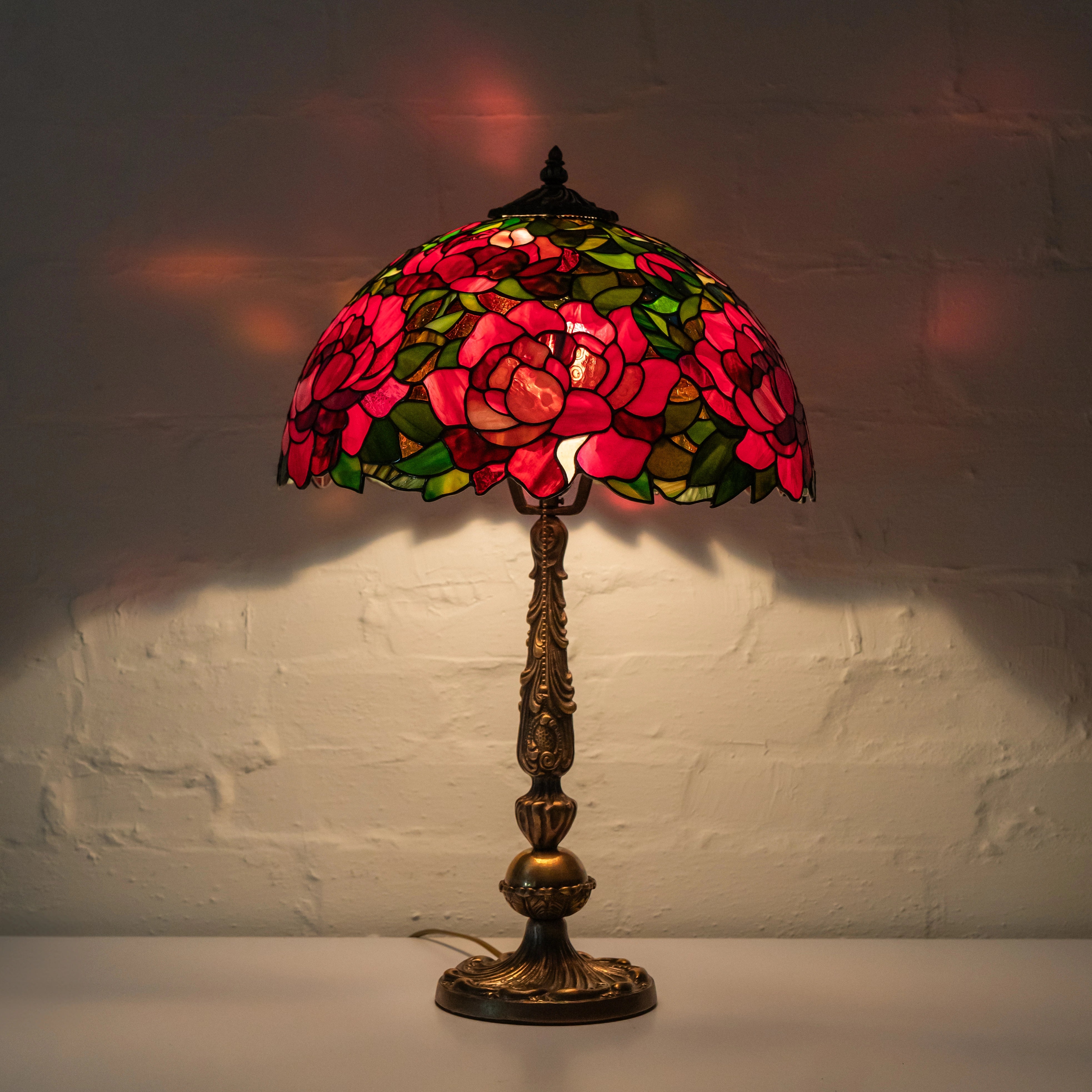 Stained glass lamp with floral design on a white brick wall background